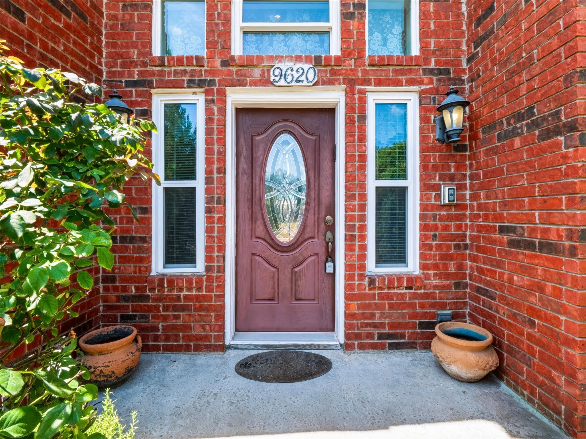 Red brick facade featuring a central entry door with an oval glass insert, flanked by two vertical windows