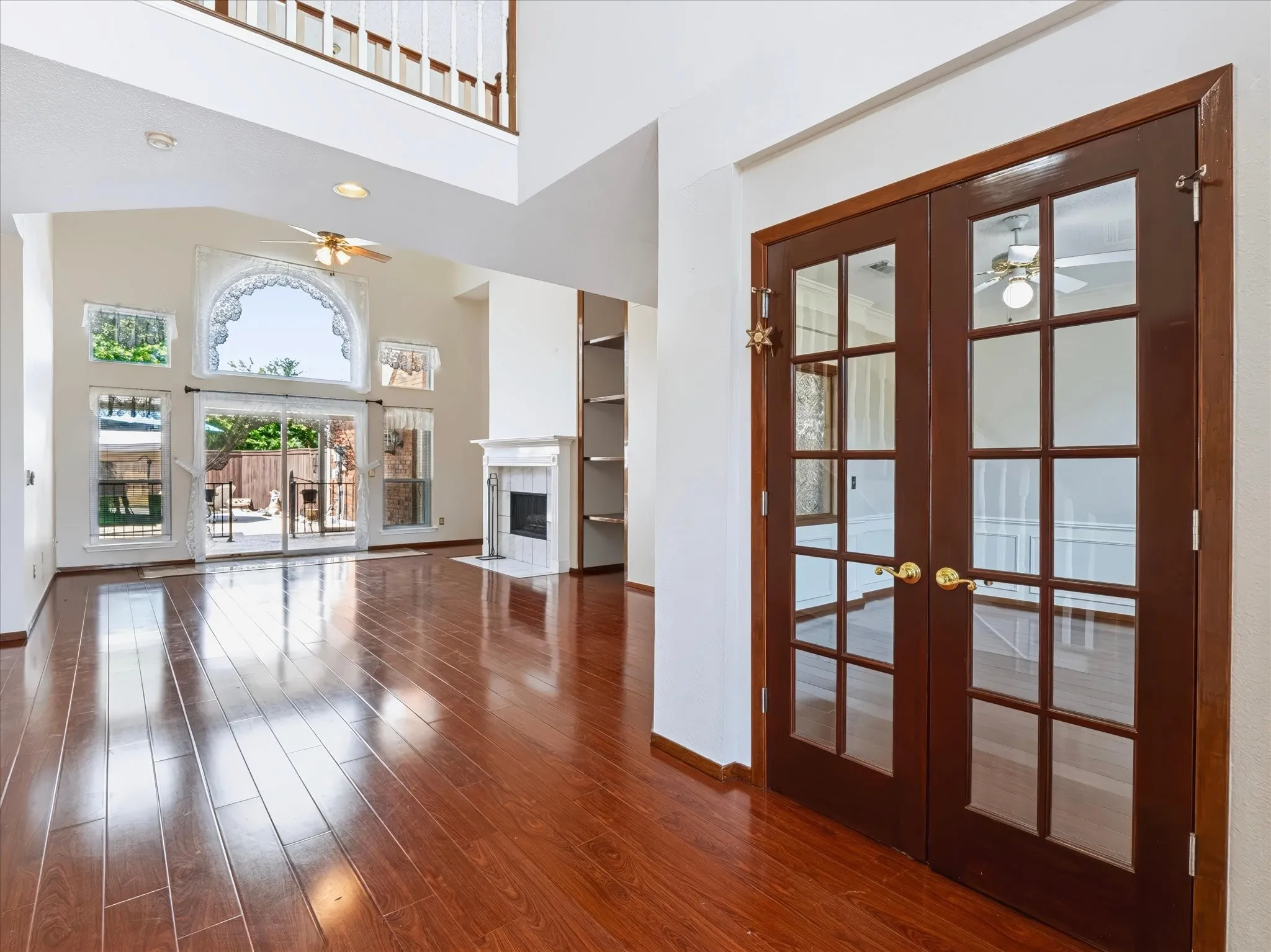 Hardwood-finish flooring, soaring ceilings, fireplace with mantel, built-in shelving, and French doors with glass panels