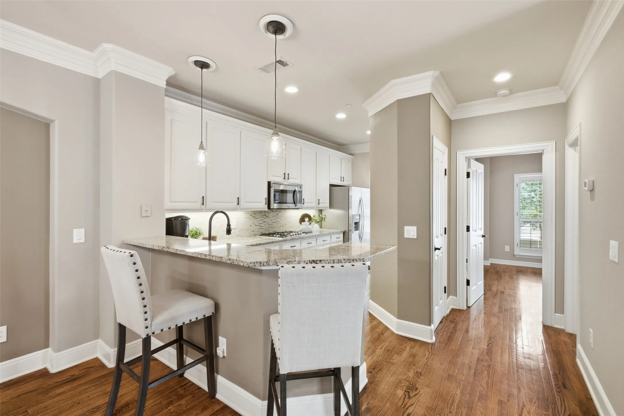 Kitchen featuring white cabinetry, granite countertops, stainless steel appliances, and wood-finish flooring
