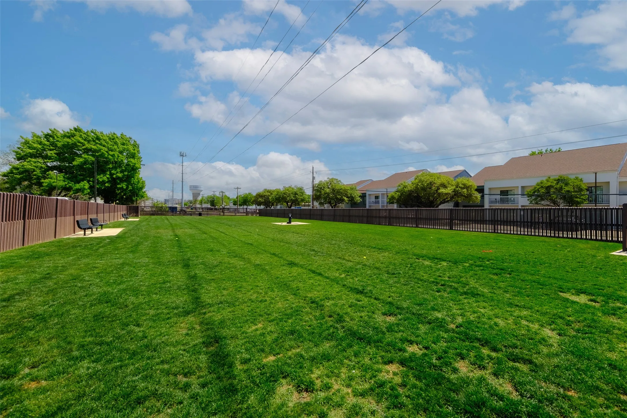 Expansive grassy area with a perimeter fence, offering open space and seating