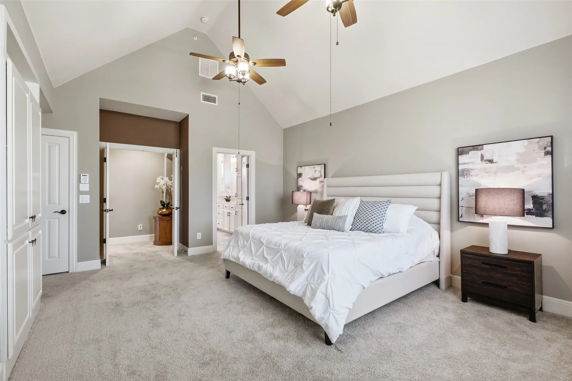 Vaulted ceiling, ceiling fans, light-toned carpeting, built-in cabinetry, and white paneled doors