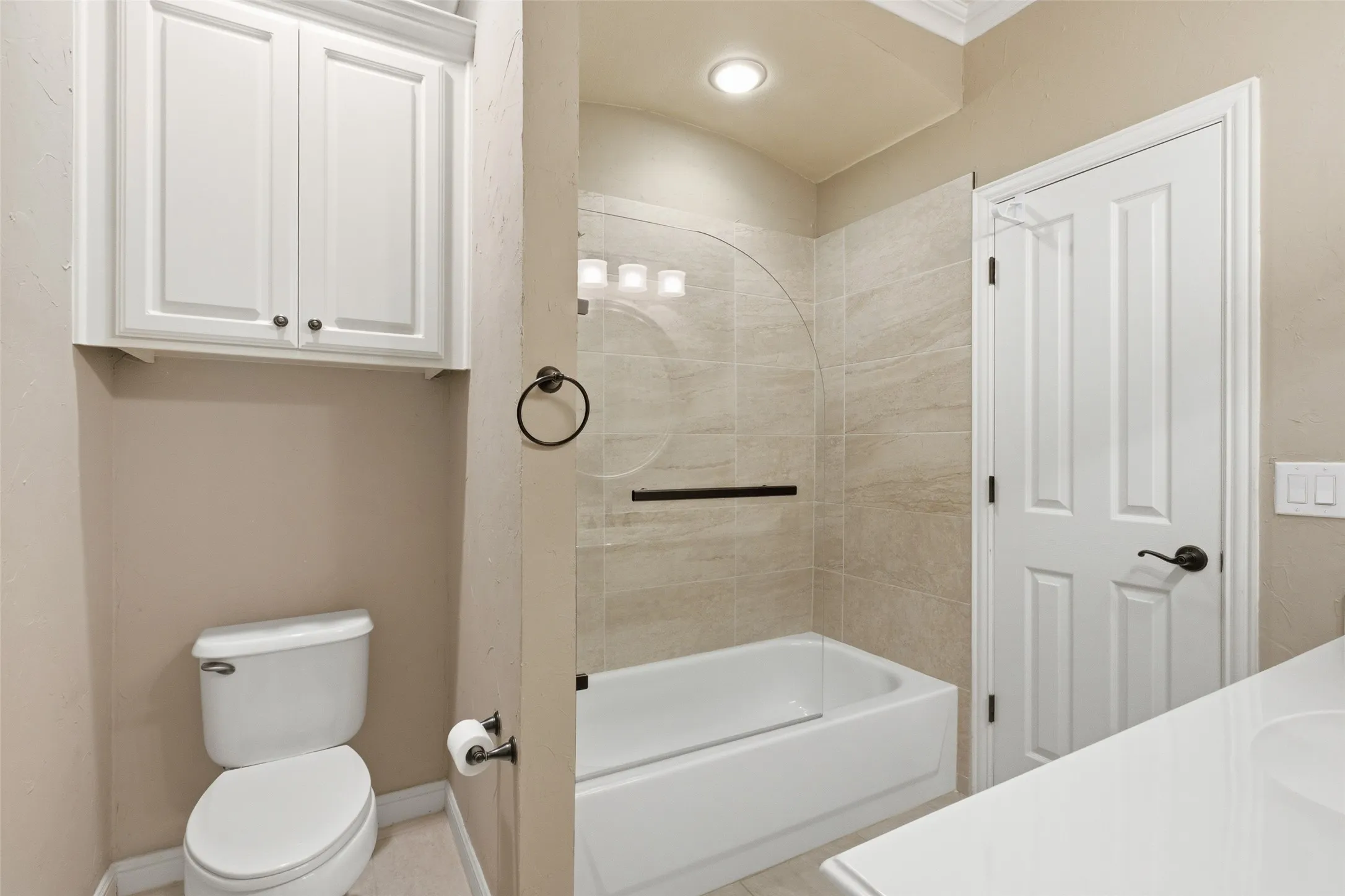 White built-in cabinetry, tiled shower and tub combination with glass enclosure, white vanity with integrated sink, and recessed lighting