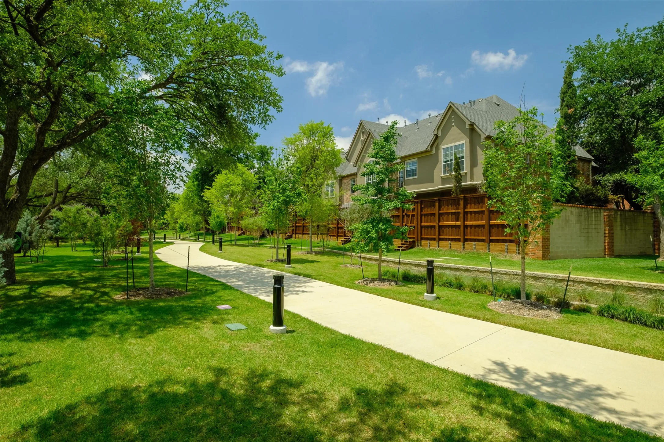 Curved concrete pathway bordered by manicured lawn and mature trees