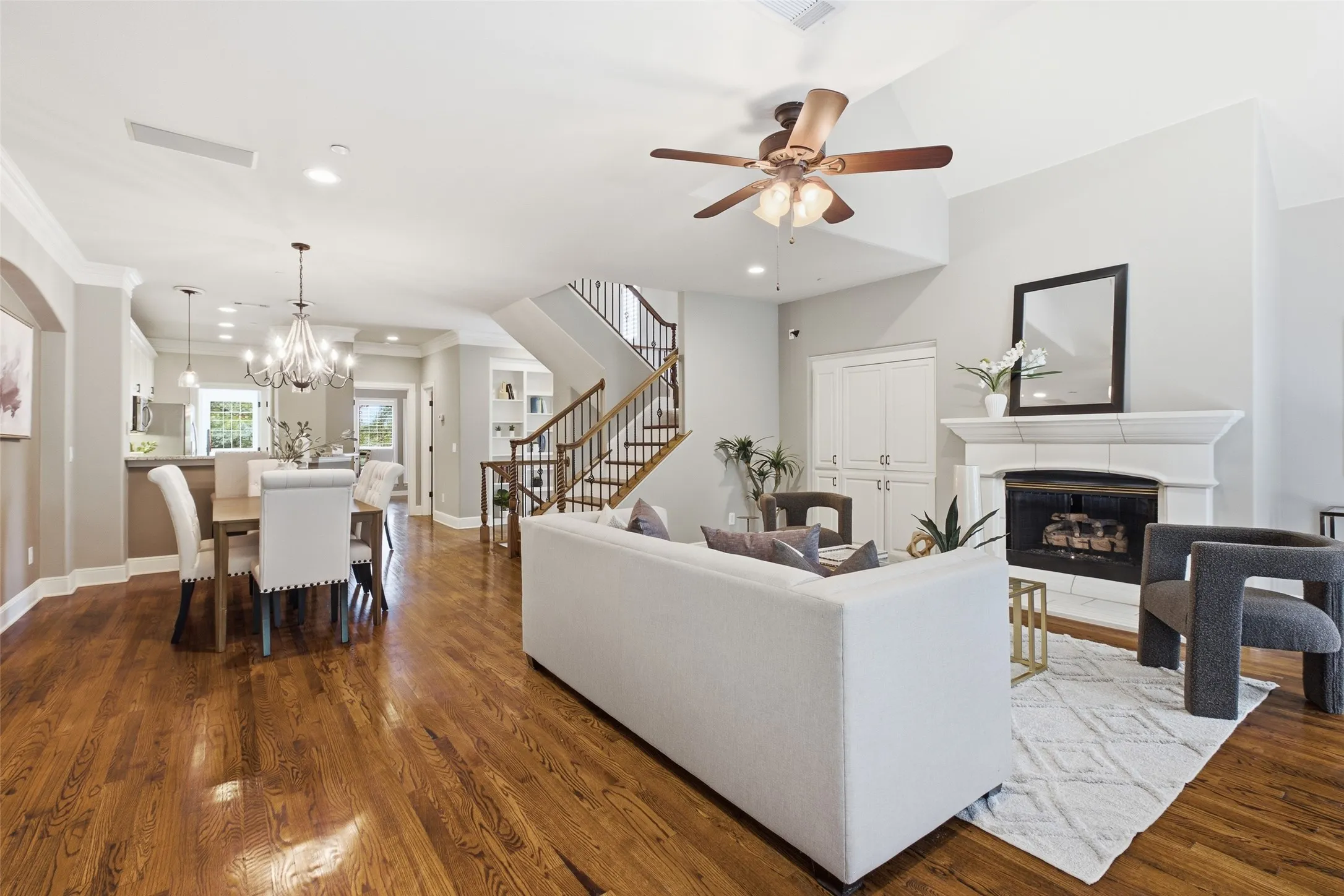 Hardwood flooring throughout, vaulted ceiling with ceiling fan, fireplace with mantel, built-in cabinetry, and open-concept design