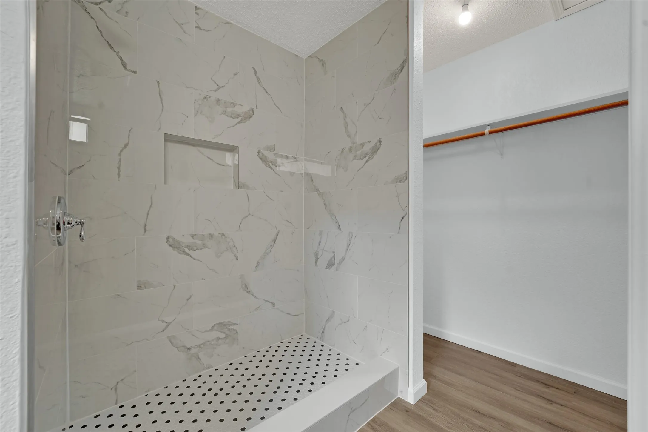 Shower enclosure featuring large format tile, built-in shower bench, and a recessed niche