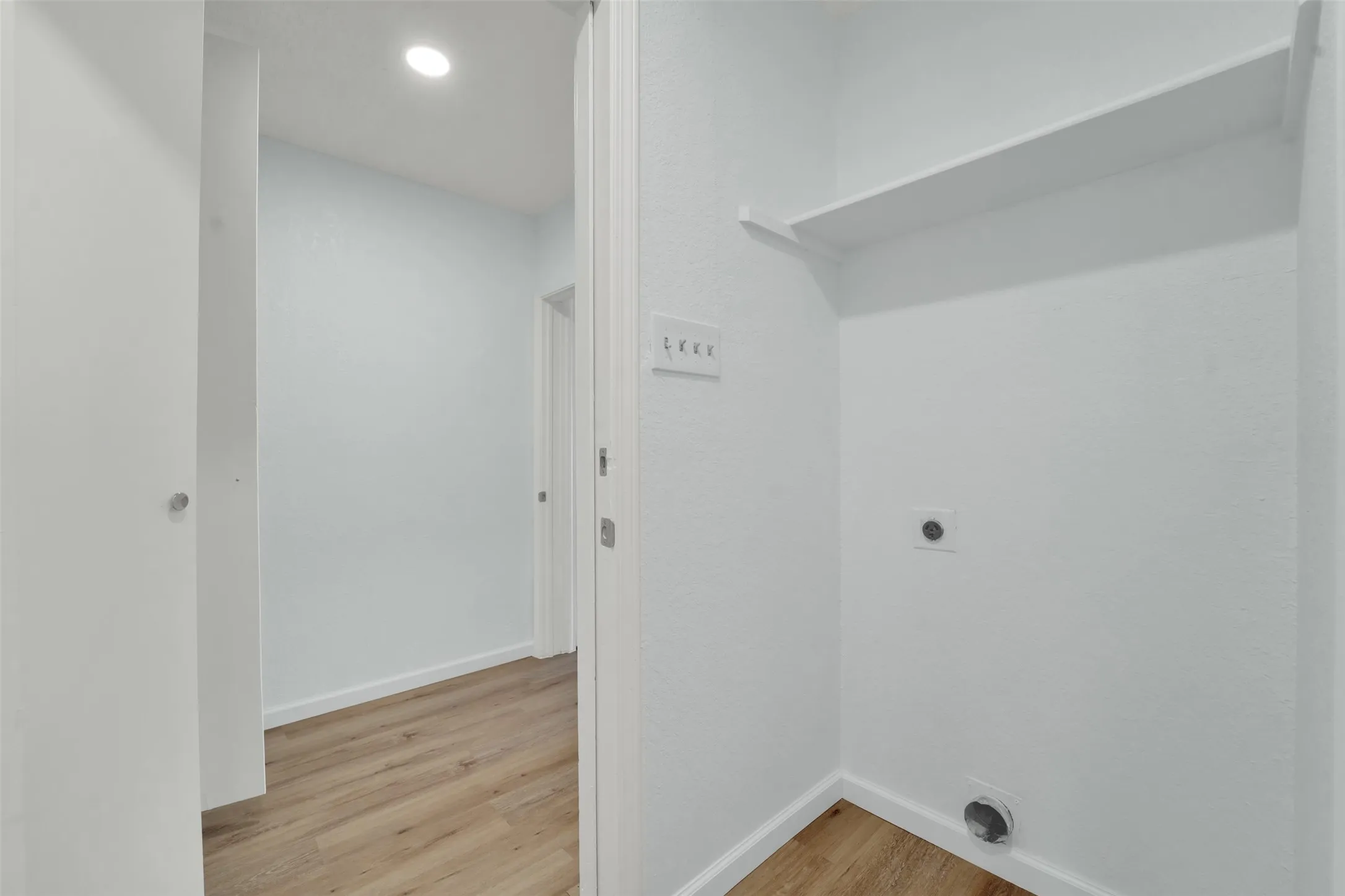Dedicated laundry space featuring a built-in shelf and wood-finish flooring