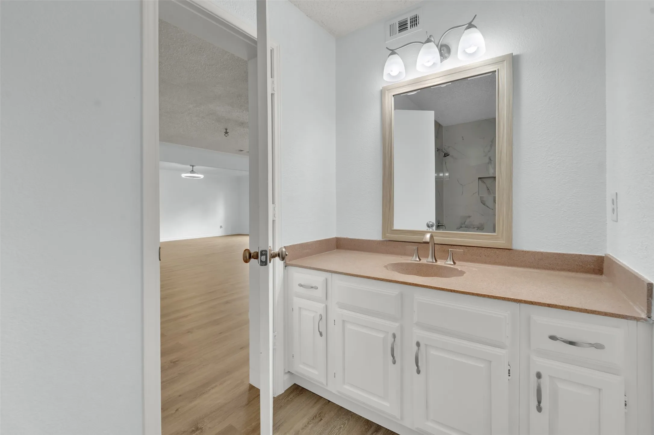 White vanity with ample cabinet storage, stone-finish countertop, and brushed nickel hardware
