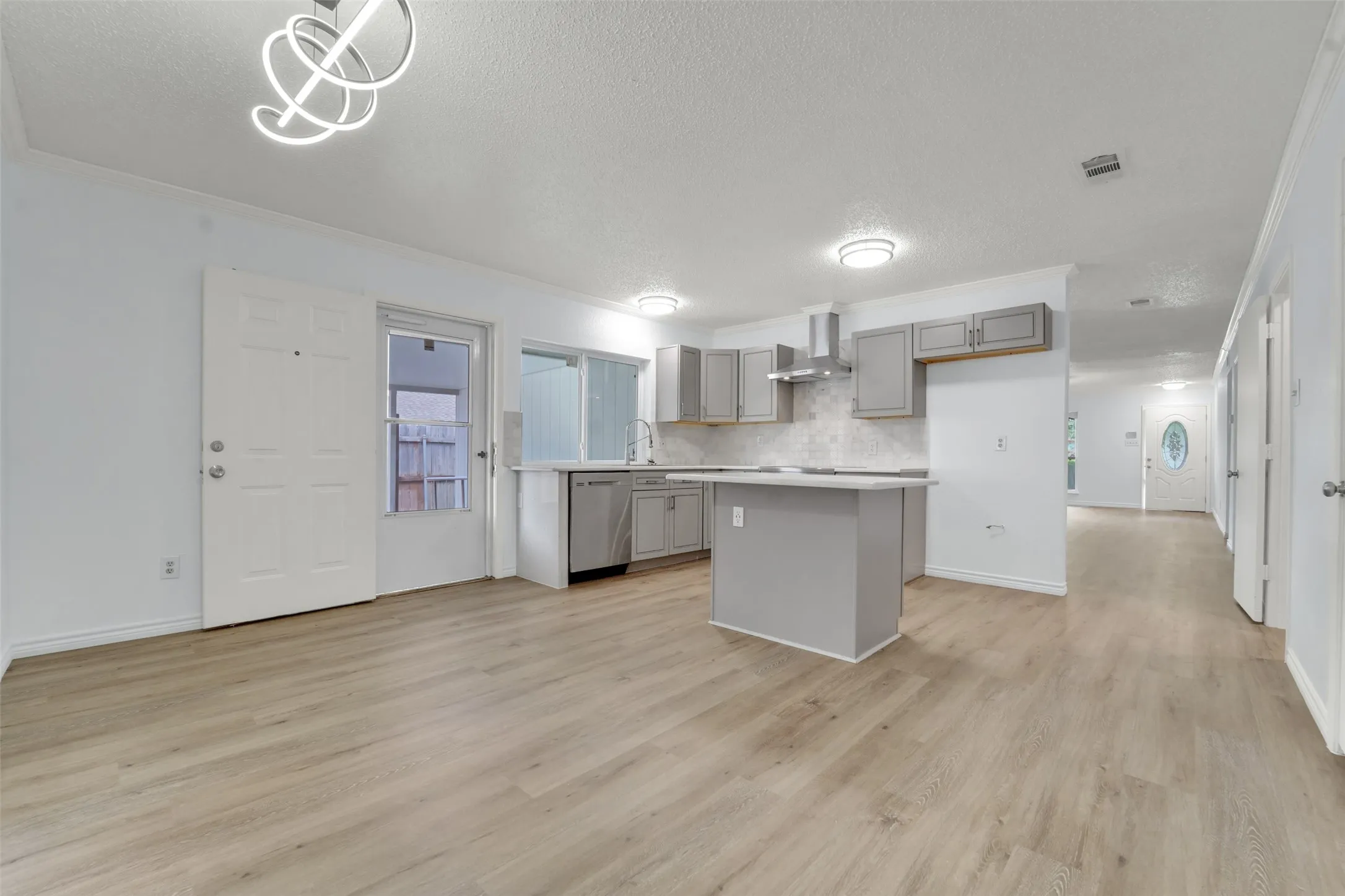 Open-concept kitchen featuring an island, gray cabinetry, stainless steel appliances, and wood-finish flooring throughout