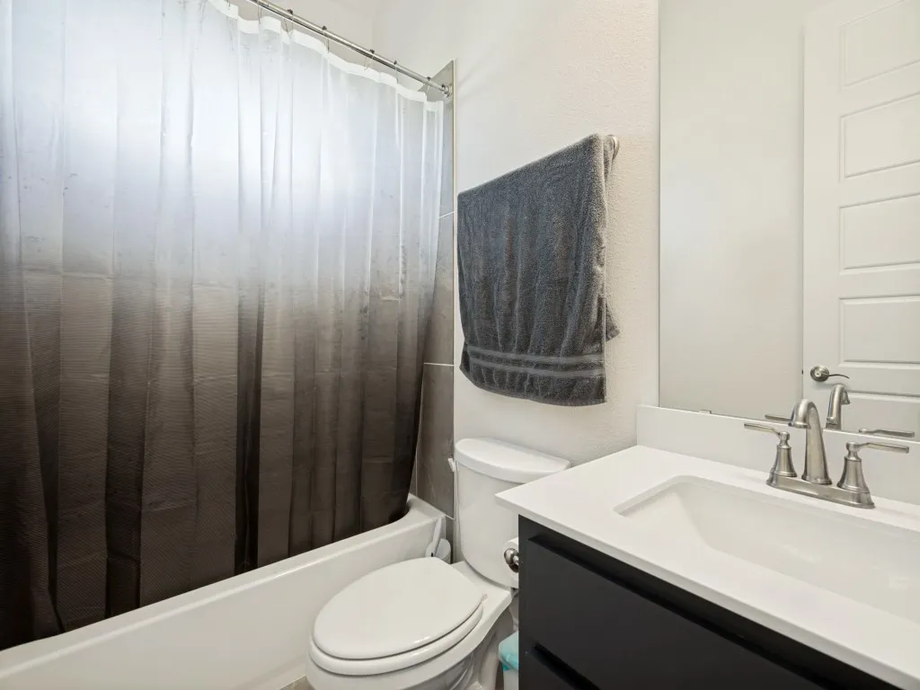 Downstairs Full Guest Bath. Integrated bathtub with shower, toilet, vanity with undermount sink, brushed nickel faucet, and framed mirror
