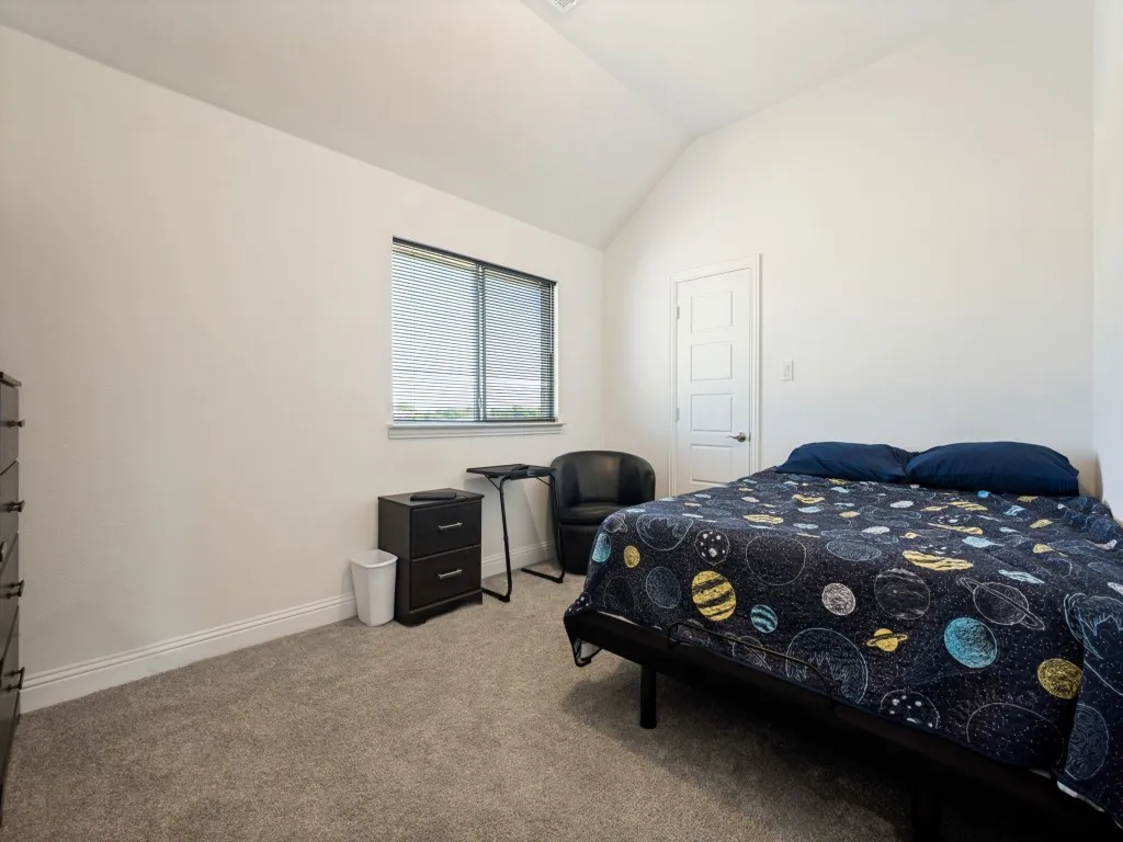 Vaulted ceiling, neutral wall paint, carpet flooring, window with blinds, panel interior door
