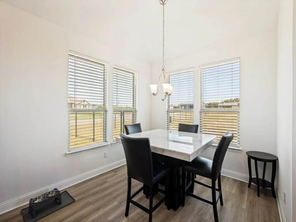 Recessed dining area with multiple windows, wood-finish flooring, and a chandelier