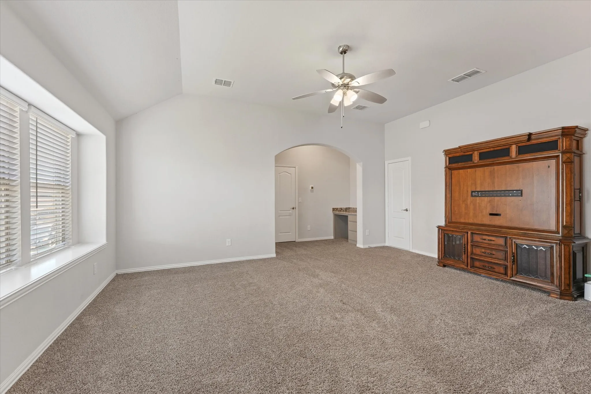 Large upstairs game room featuring a built-in desk, full bathroom access, abundant natural light, and plenty of space for entertaining or relaxing.