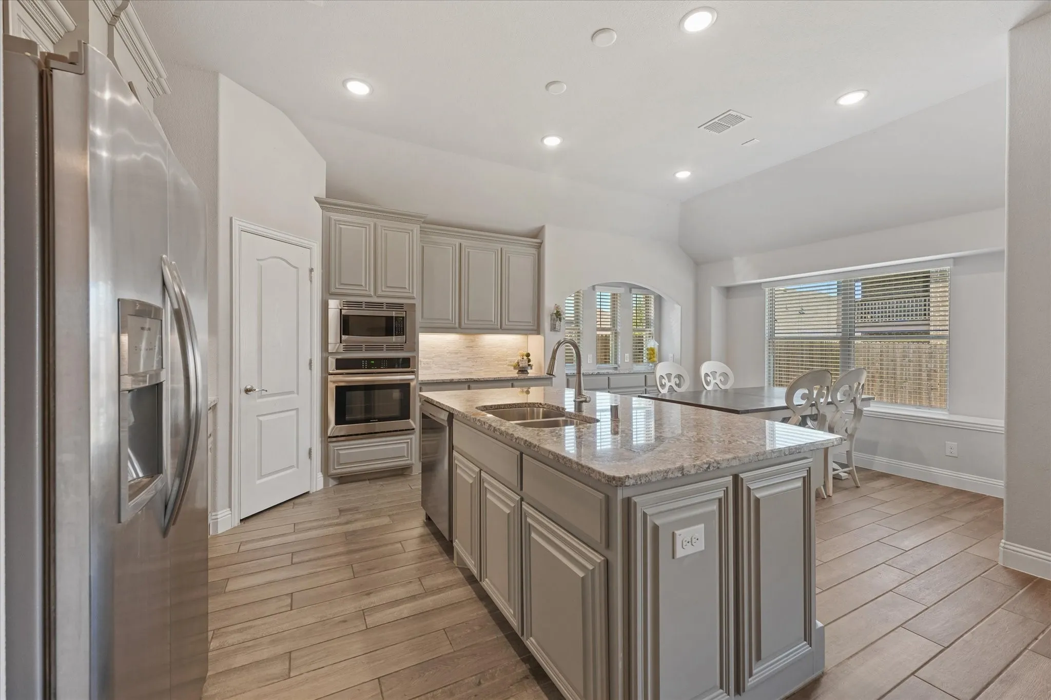 Beautifully appointed gourmet kitchen with granite countertops, abundant cabinetry, stainless appliances, large island, and recessed lighting.