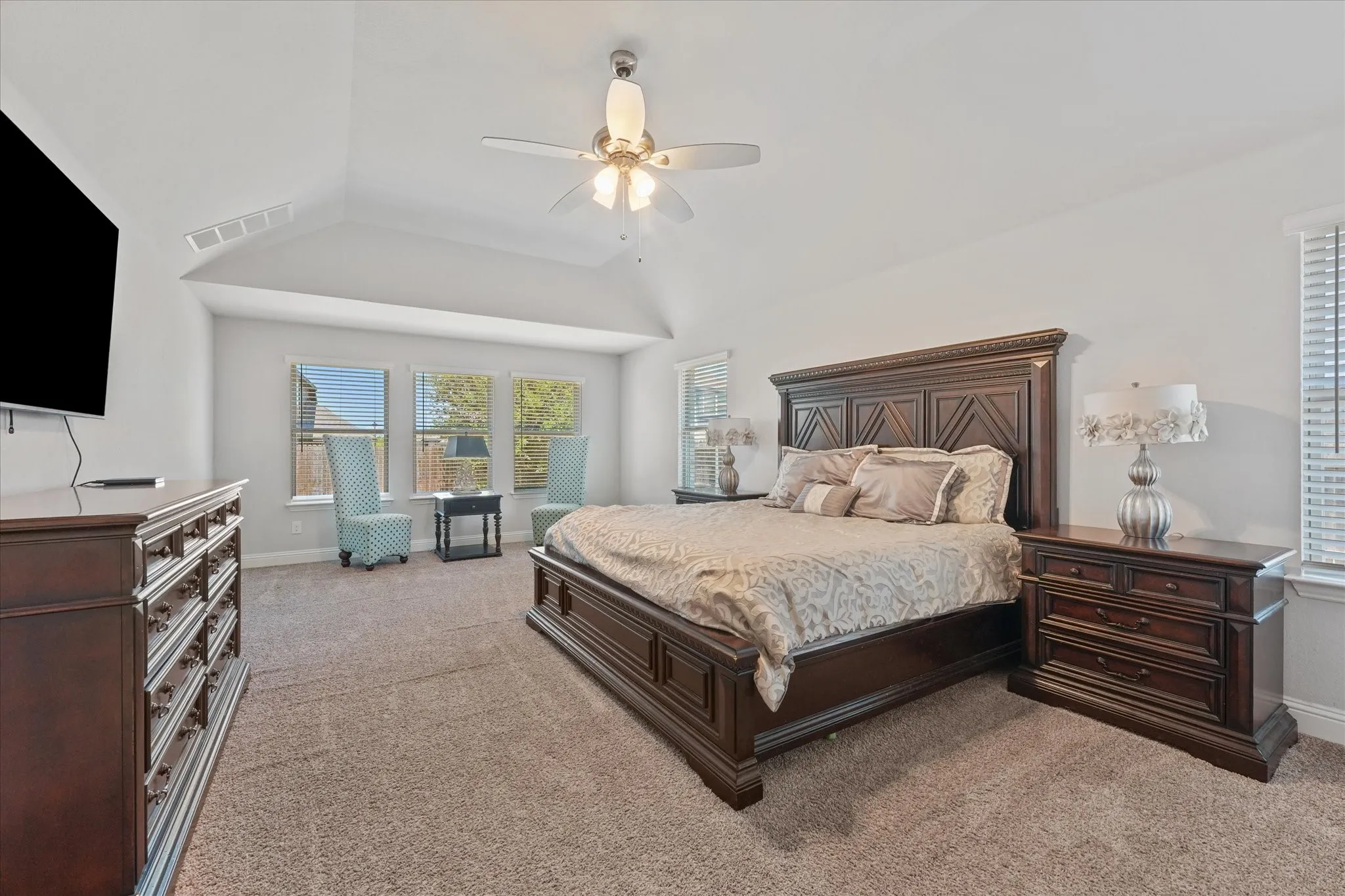 Oversized Primary Suite featuring vaulted ceilings, abundant natural light, generous space, and plush carpeting.
