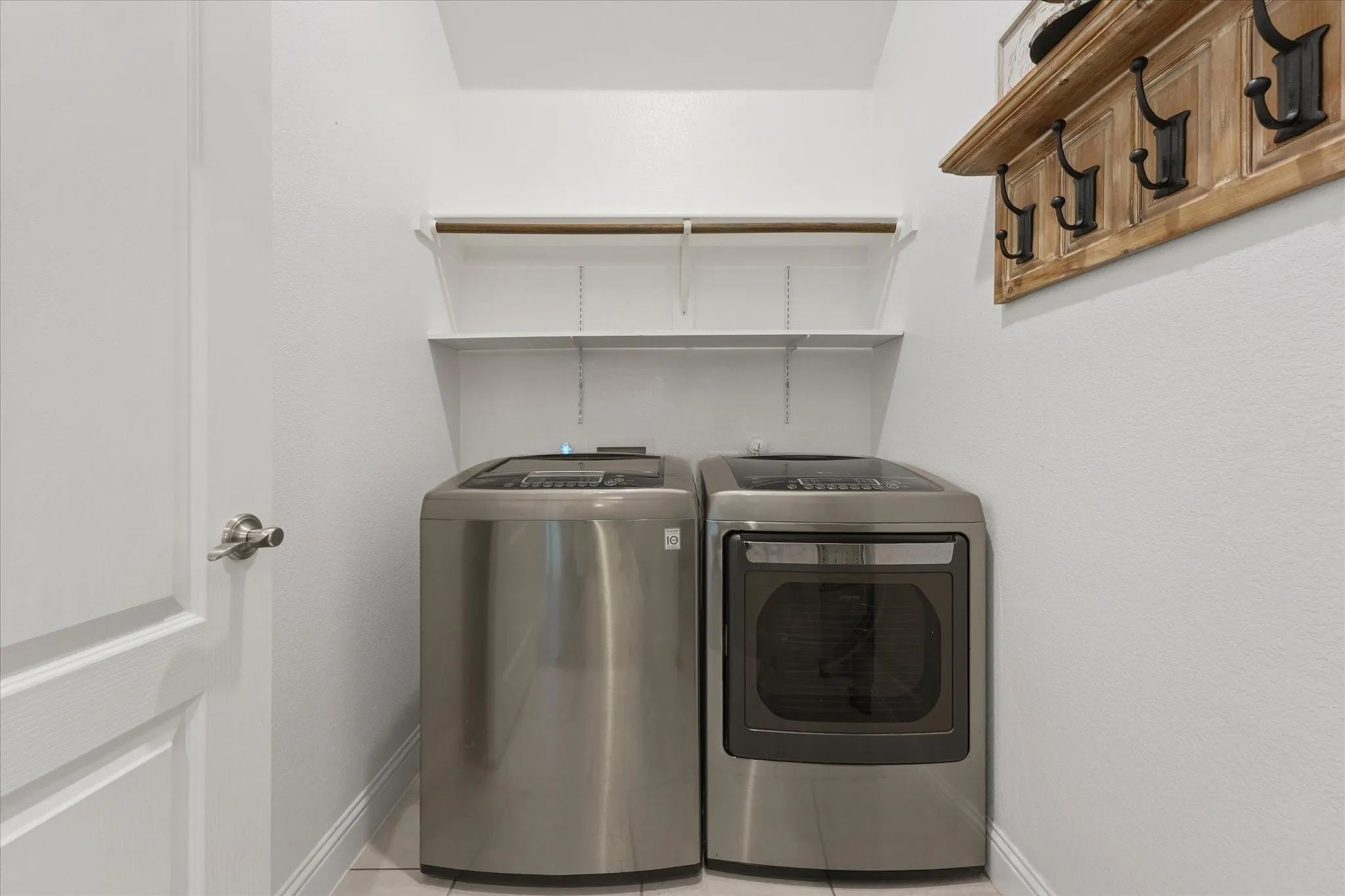 Laundry area featuring white walls, open shelving, and a hanging rod