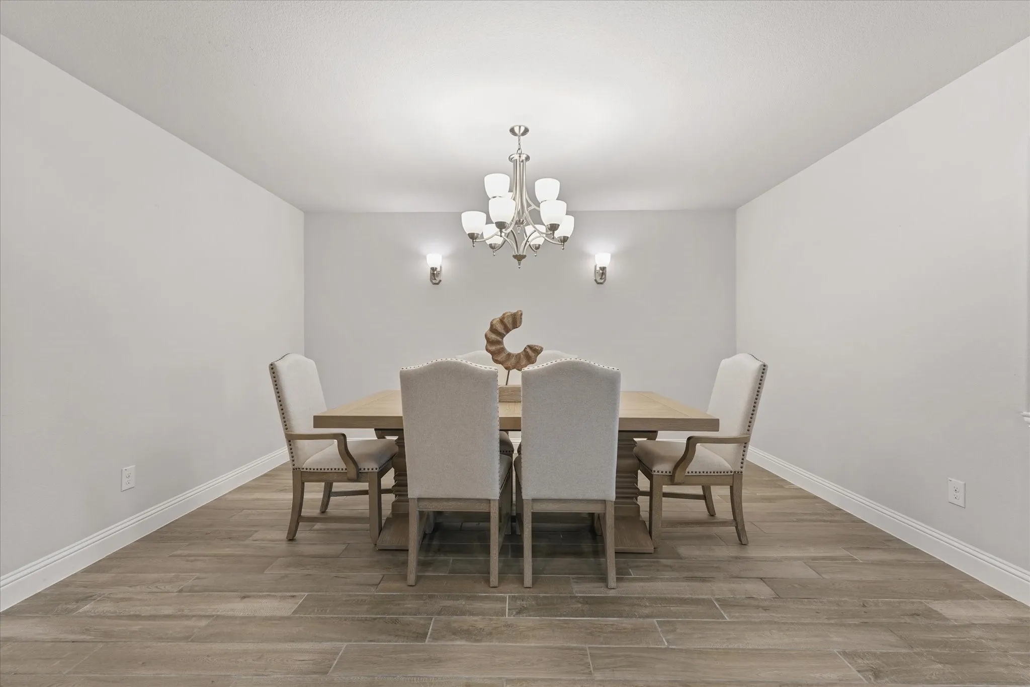 Recessed lighting, wood-look tile plank flooring, chandelier, and wall sconces