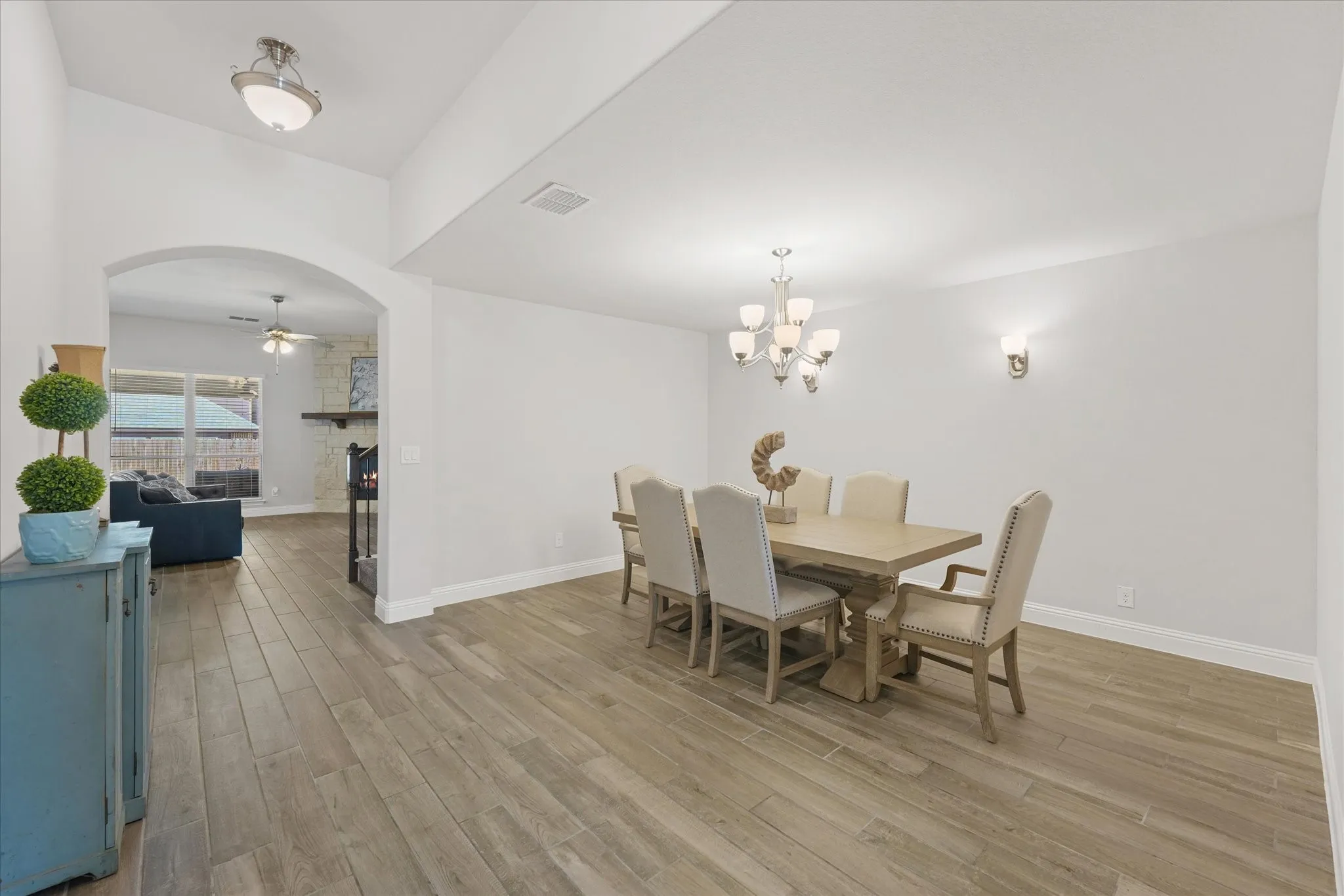 Plenty of room to host your large family and/or friends in this spacious dining room featuring elegant lighting, abundant natural light, and warm wood-look tile plank flooring.