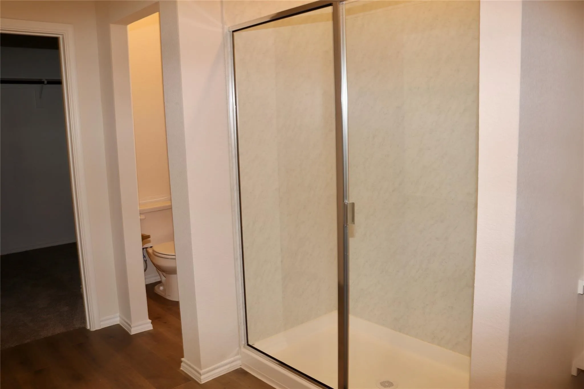 Glass-enclosed shower with a smooth base and light-toned surround