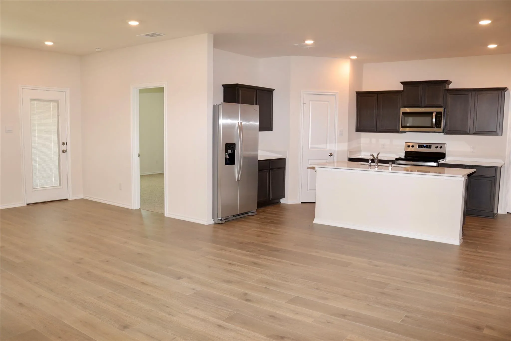 Open concept living space featuring wood-finish flooring, recessed lighting, and a modern kitchen