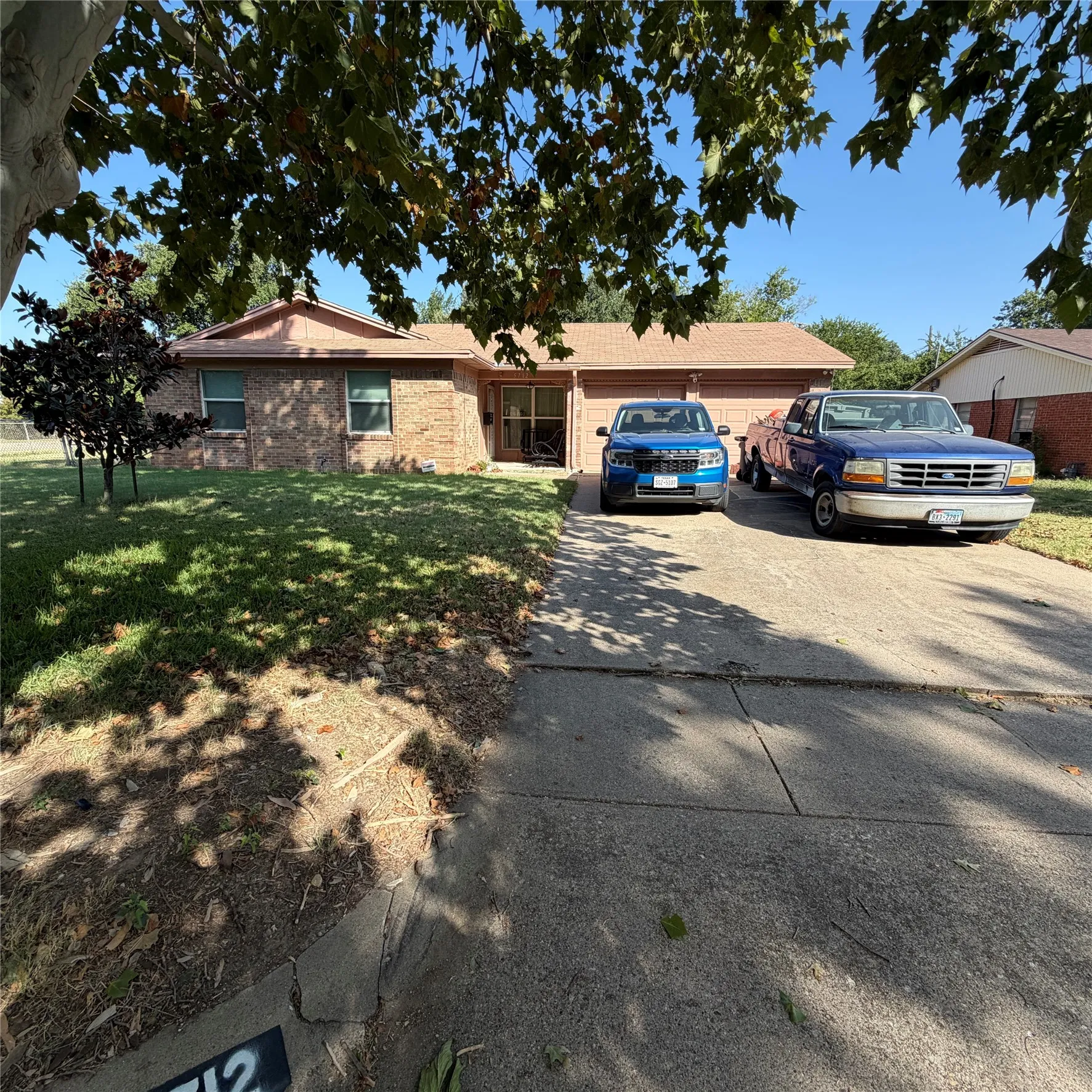 Brick exterior with an attached garage, concrete driveway, and a front lawn