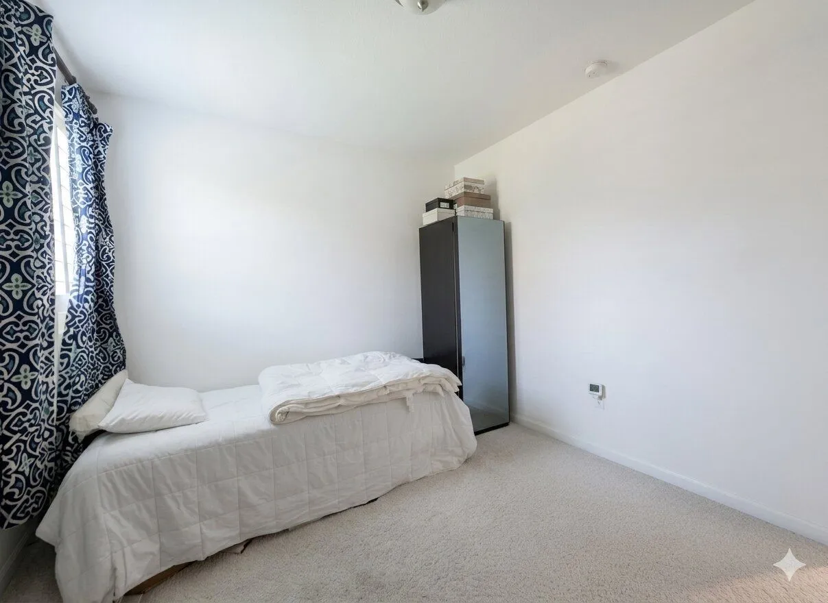 Carpeted flooring, white walls, and a window with patterned drapes