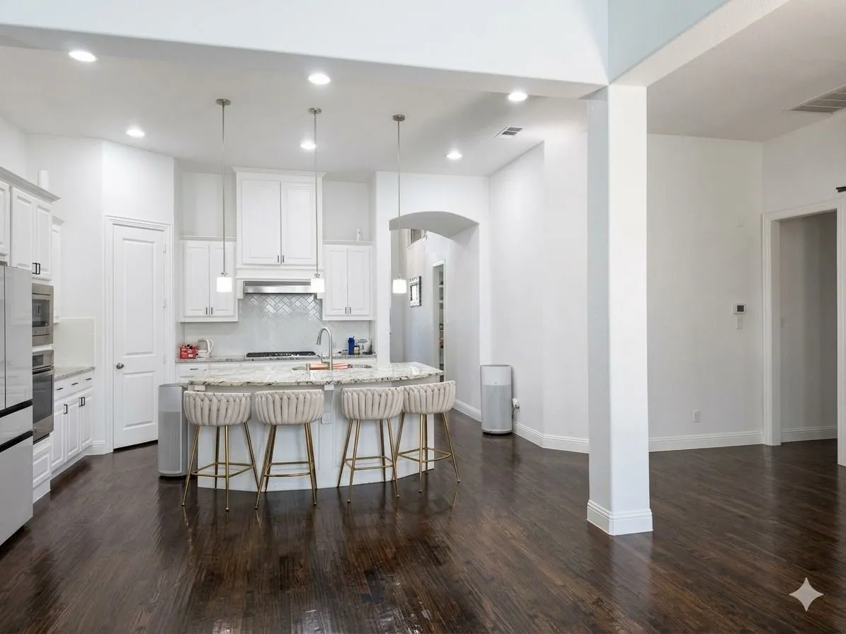 Kitchen featuring white cabinetry, a curved island with integrated seating, stainless steel appliances, a tile backsplash, and recessed lighting