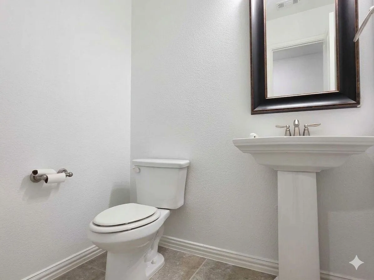 Pedestal sink with a dark-framed mirror, white toilet, and tile flooring