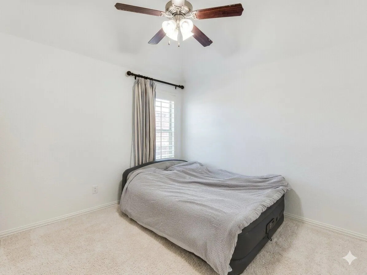 Carpeted flooring, white walls, window with plantation shutters, and a ceiling fan with light fixture