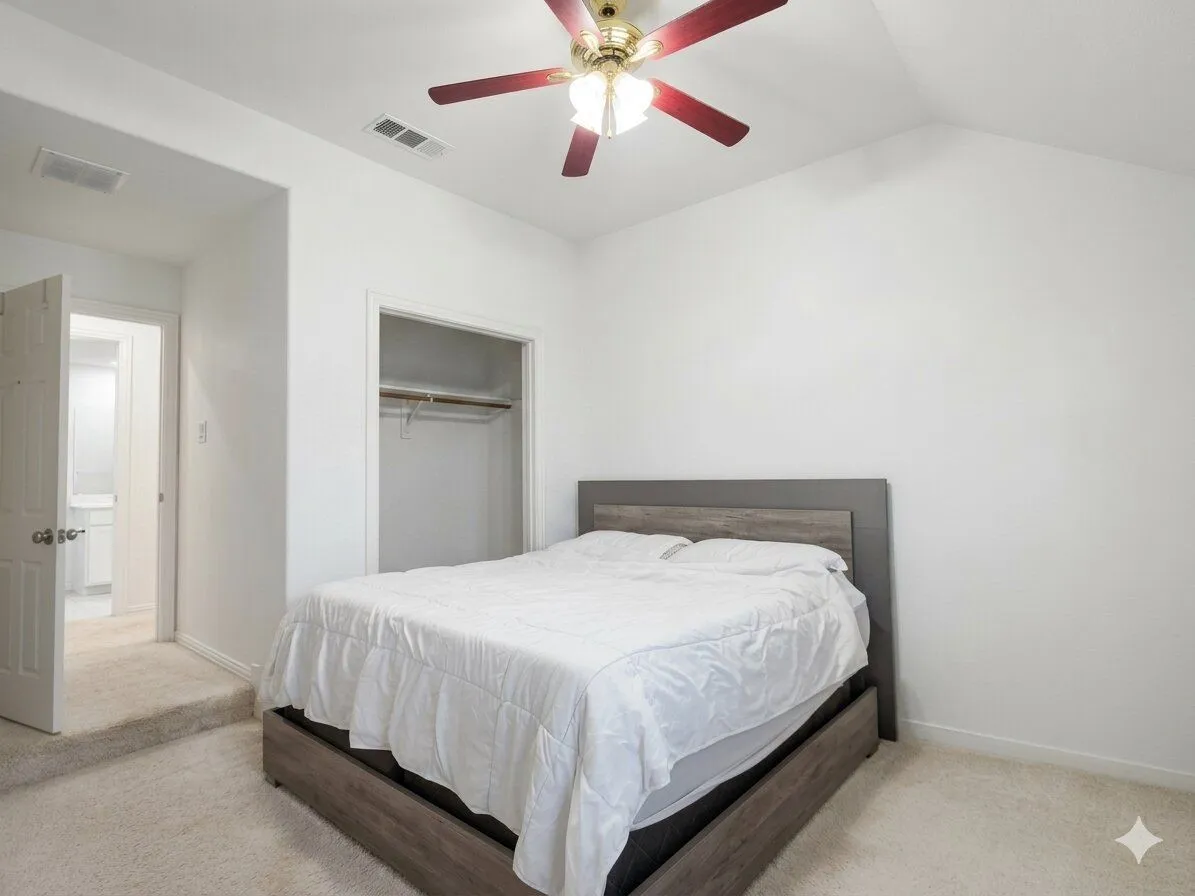 Vaulted ceiling, ceiling fan, white walls, carpet flooring, and an open closet with a built-in rod