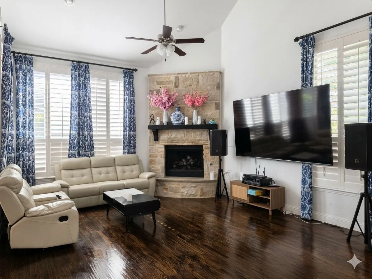 Vaulted ceiling with a ceiling fan, stone-clad fireplace, wood-finish flooring, and white plantation shutters