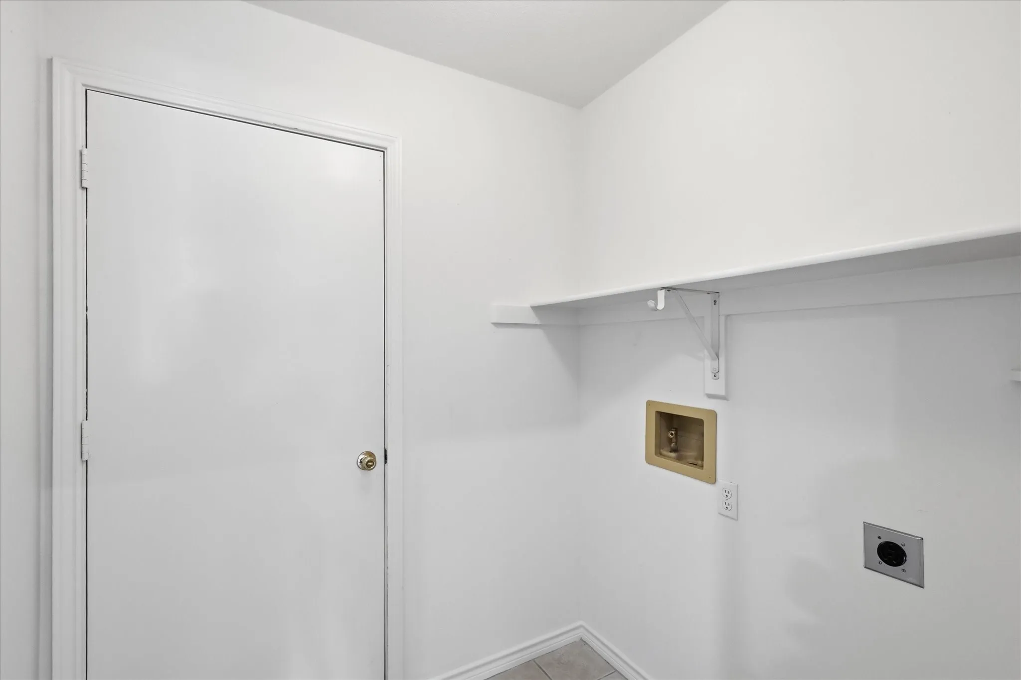 Utility area featuring a white door, shelving, and essential hookups