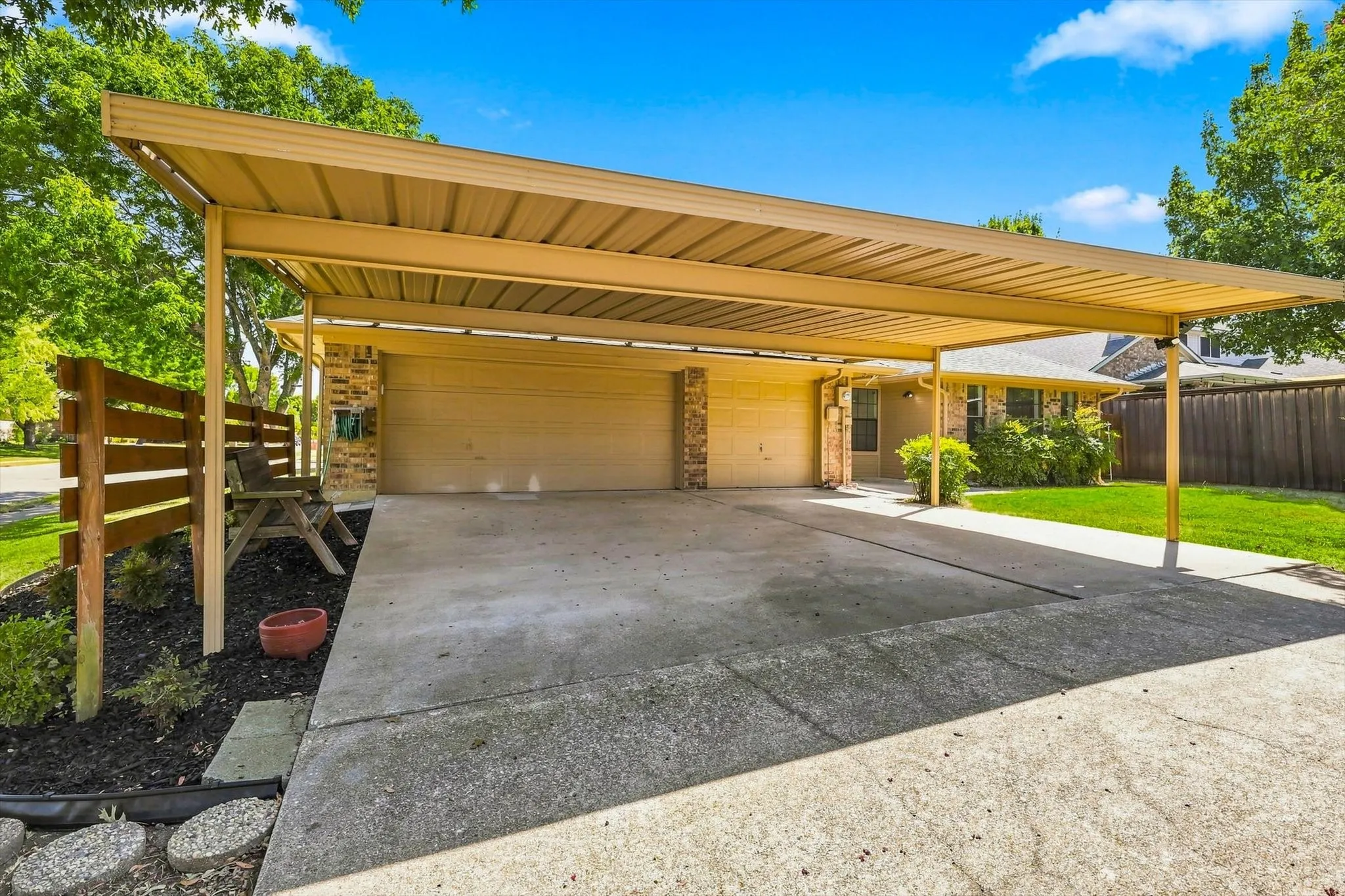 Expansive carport providing covered parking, attached three-car garage, brick facade, and concrete driveway