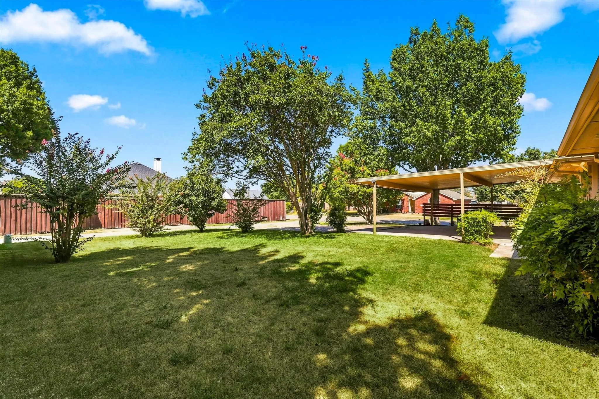 Expansive lawn area with mature trees and a covered patio