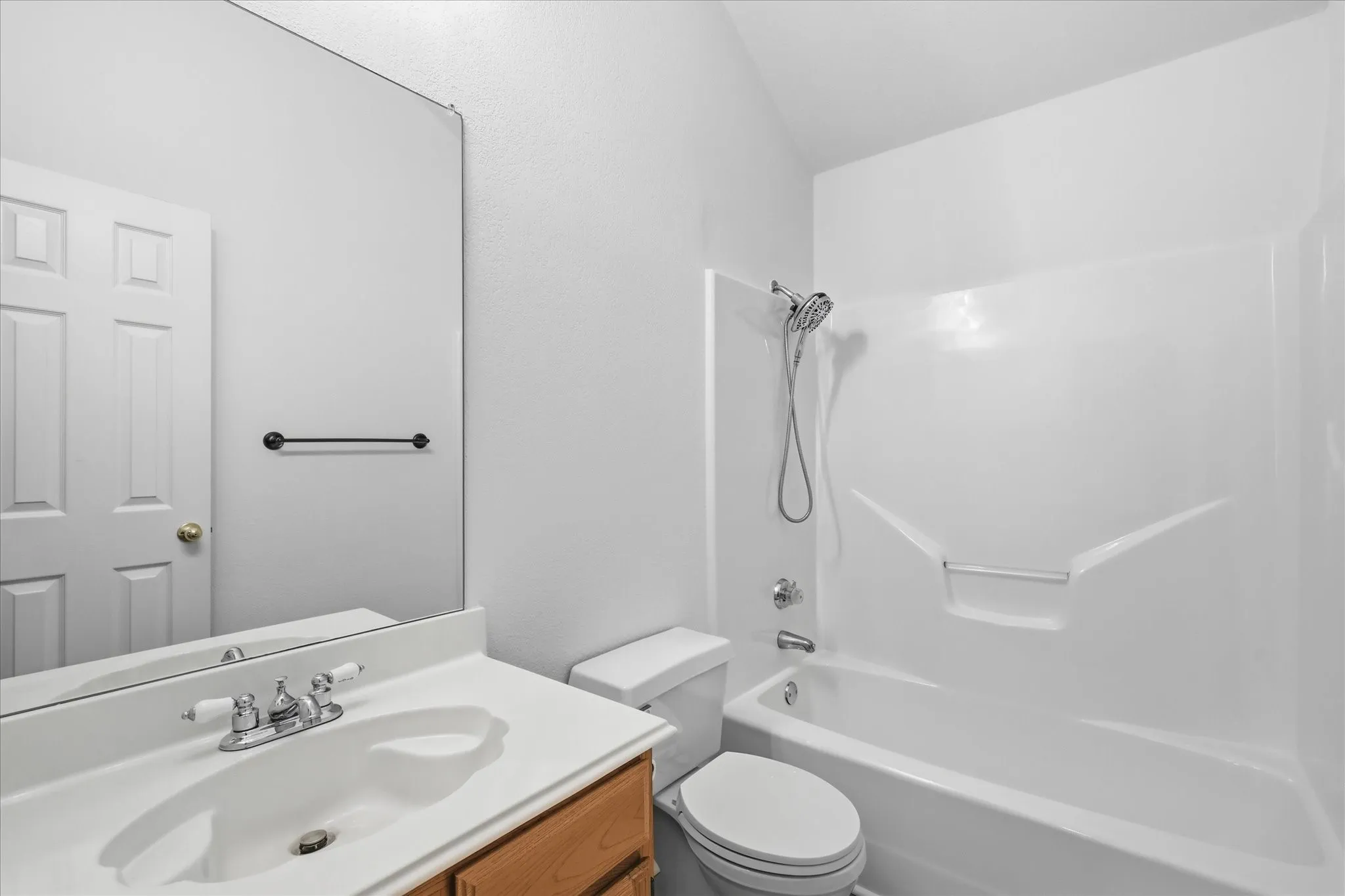 Bathroom featuring a built-in bathtub with shower, toilet, and vanity with an integrated sink