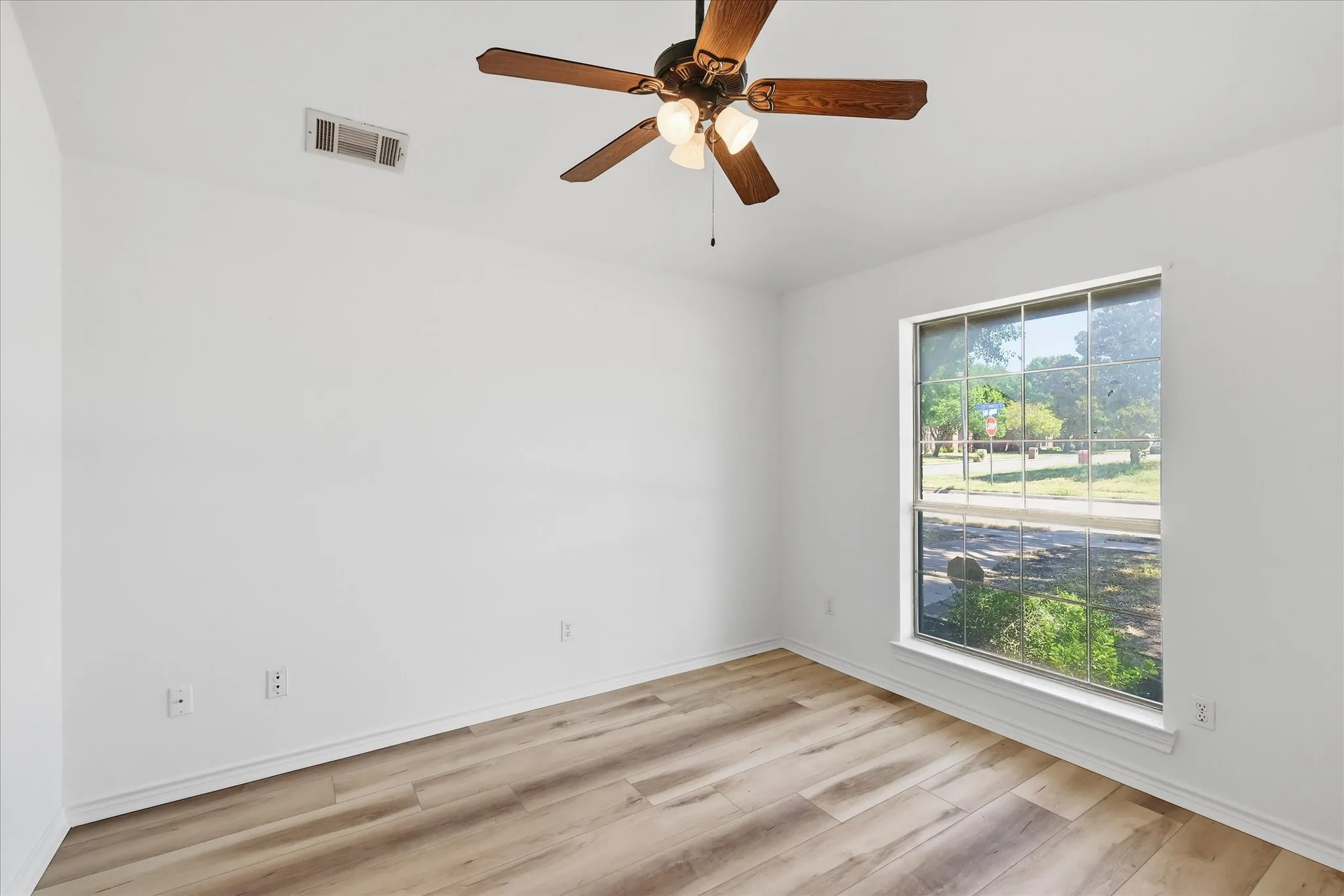 Wood-finish flooring, overhead ceiling fan with lighting, and a single window