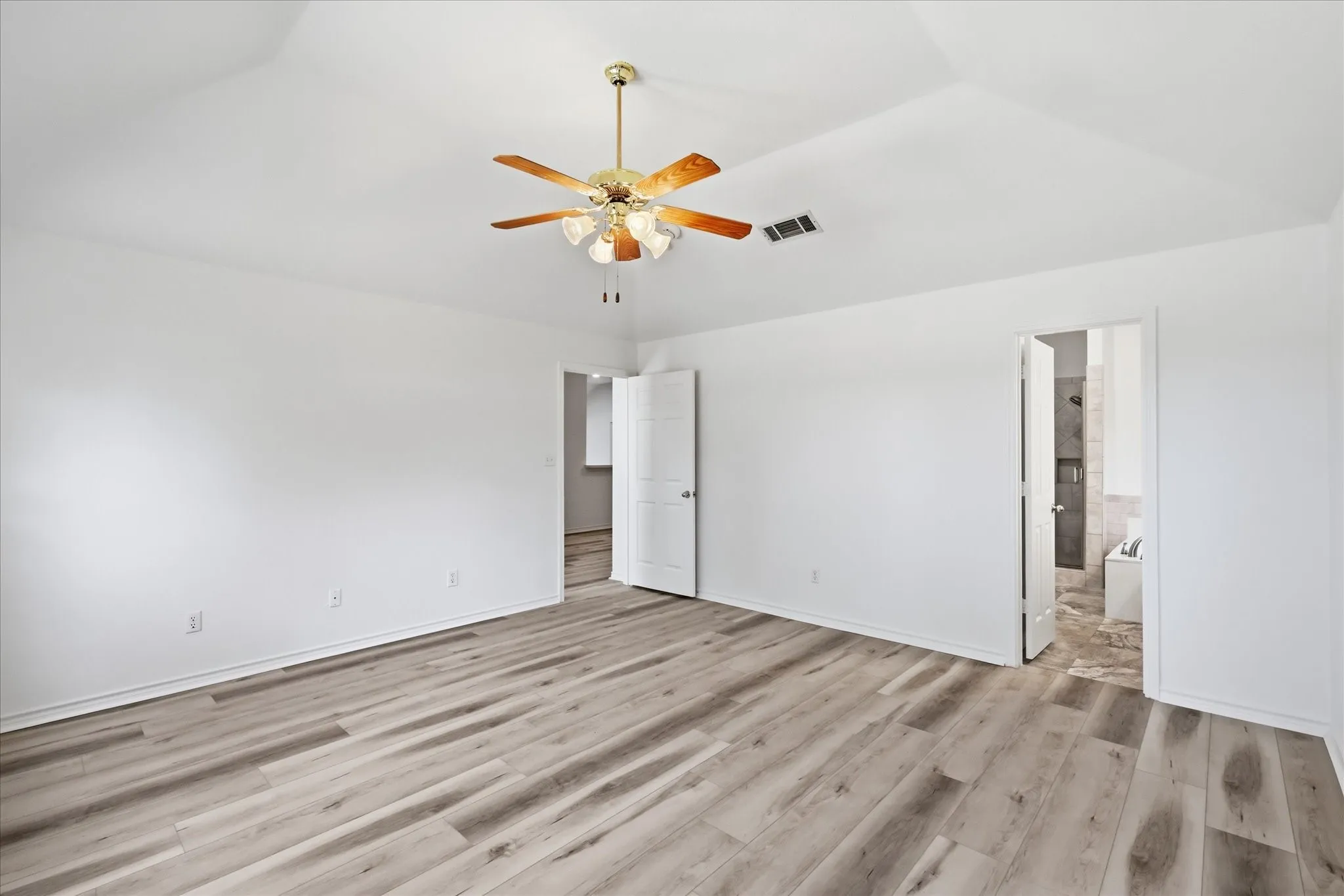 Tray ceiling, wood-finish flooring, ceiling fan, white paneled doors, and bright white walls