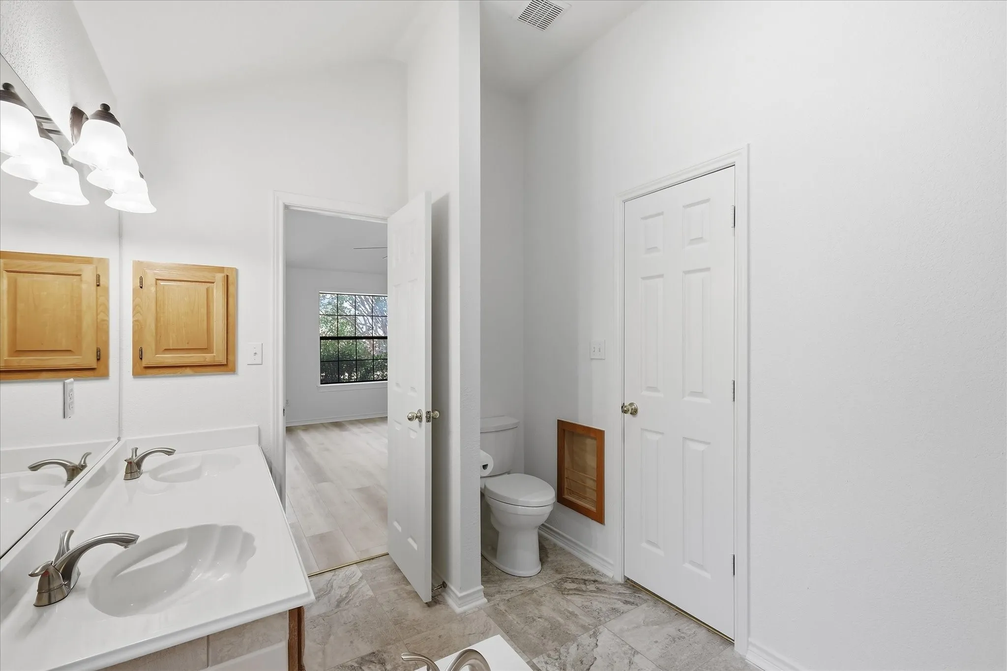 Dual vanity with integrated sinks, brushed nickel faucets, and light wood-finish cabinetry