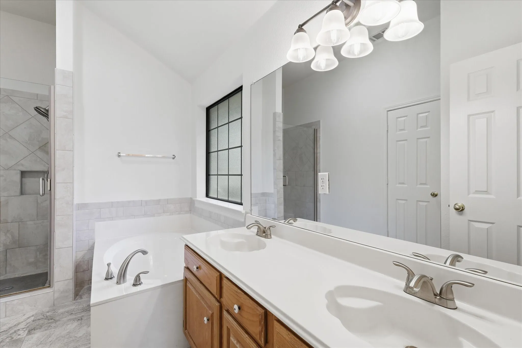 Dual vanity with white countertops, wood-finish cabinetry, and brushed nickel fixtures