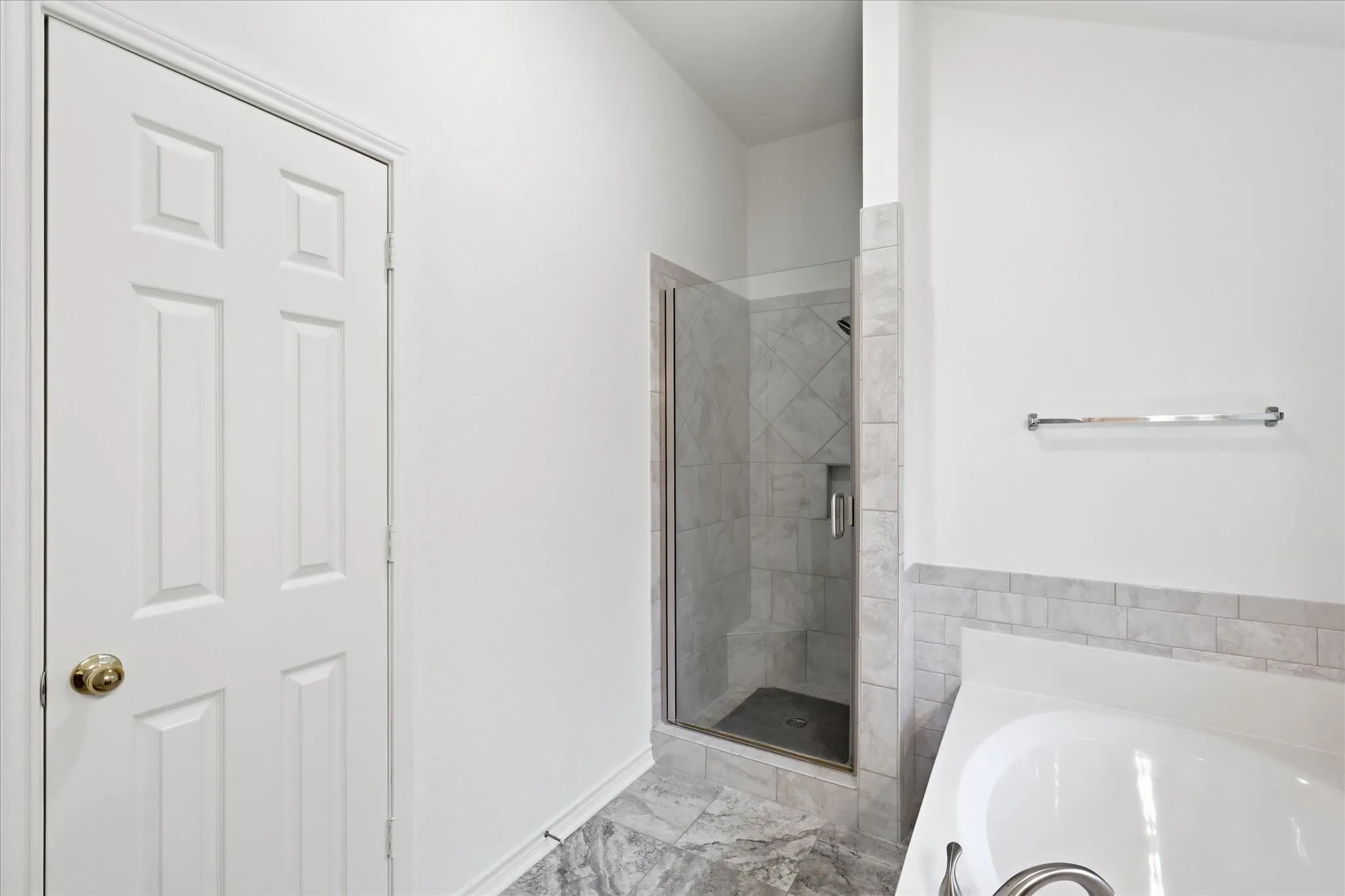 Walk-in shower with clear glass enclosure, tiled walls, and built-in shelf