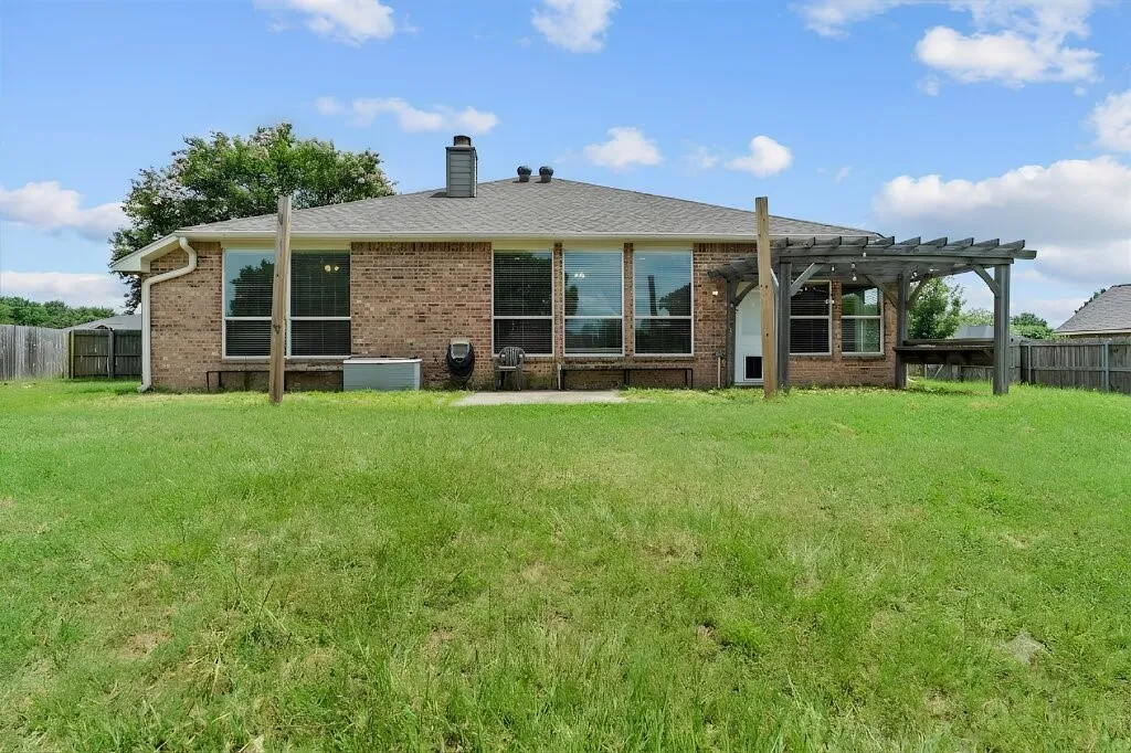 Brick exterior with multiple windows, a rear patio, and a wood pergola structure