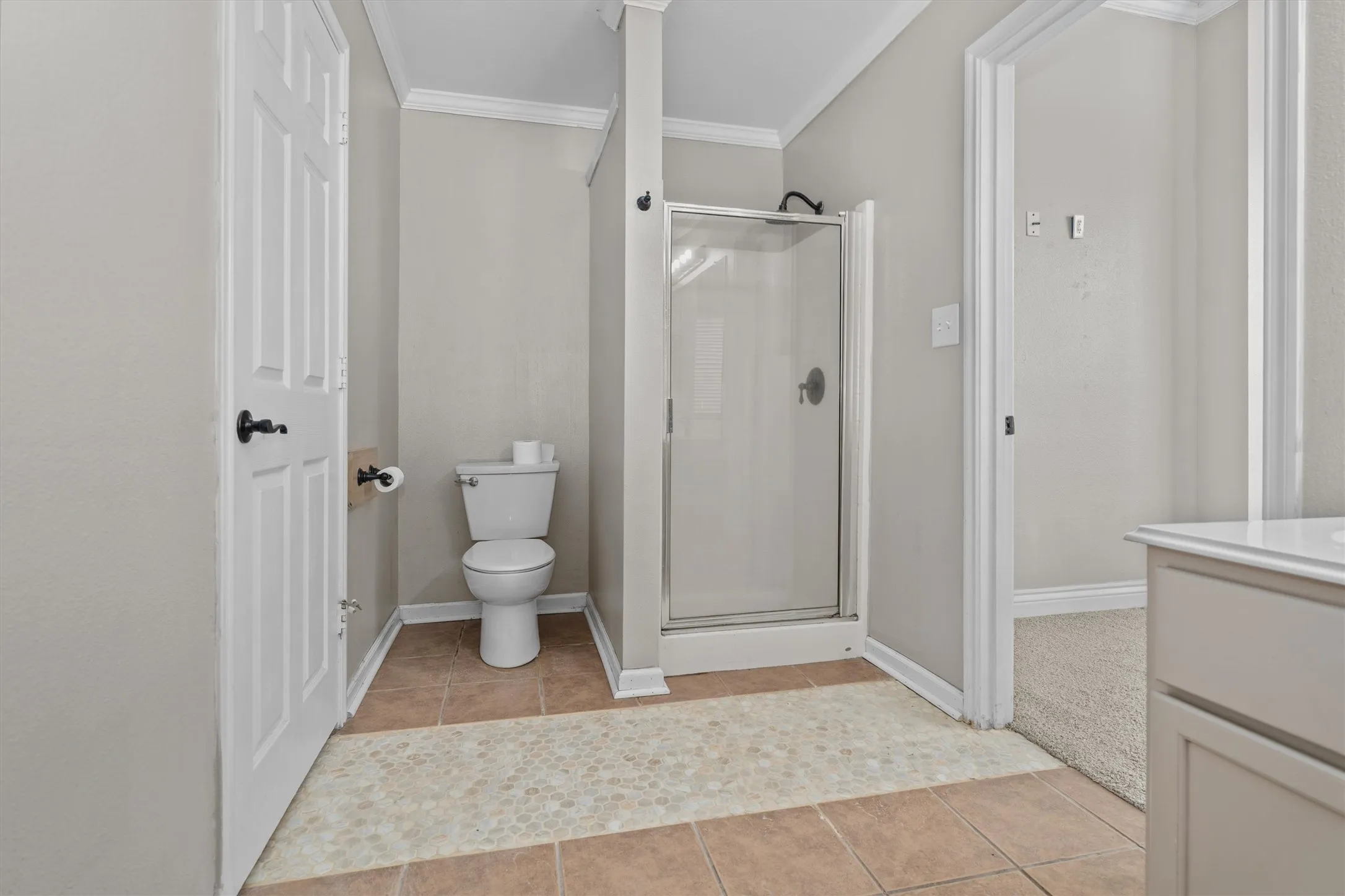 Spacious primary bathroom featuring a walk-in shower with glass enclosure and chrome hardware, dual-sink vanity with ample storage, ceramic tile flooring, and abundant natural lighting from multiple windows