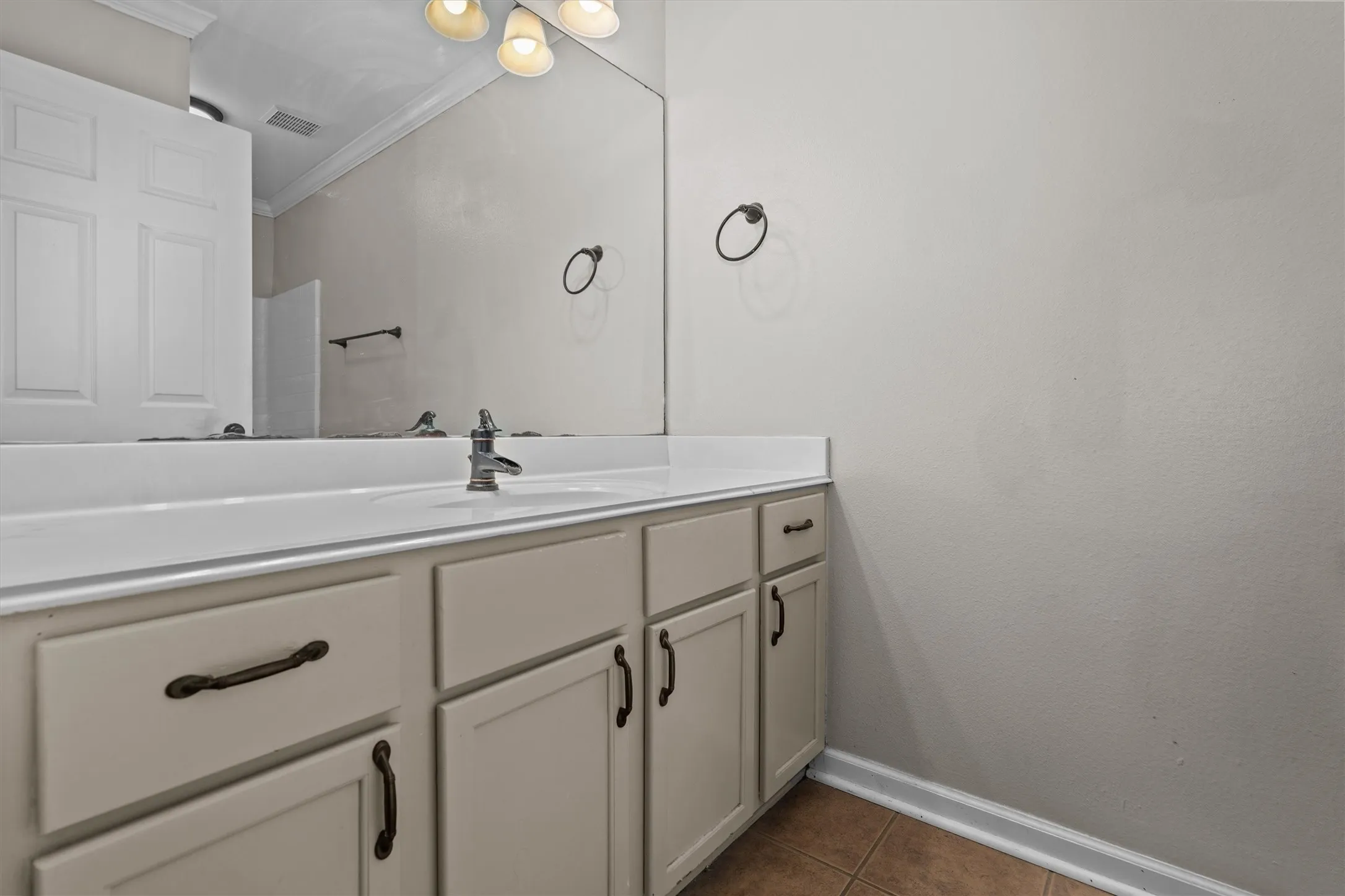 Spa-inspired primary bathroom vanity featuring a soft-finish cabinetry base with ample storage, a streamlined white countertop with integrated sink, and matte black hardware and faucet fixtures