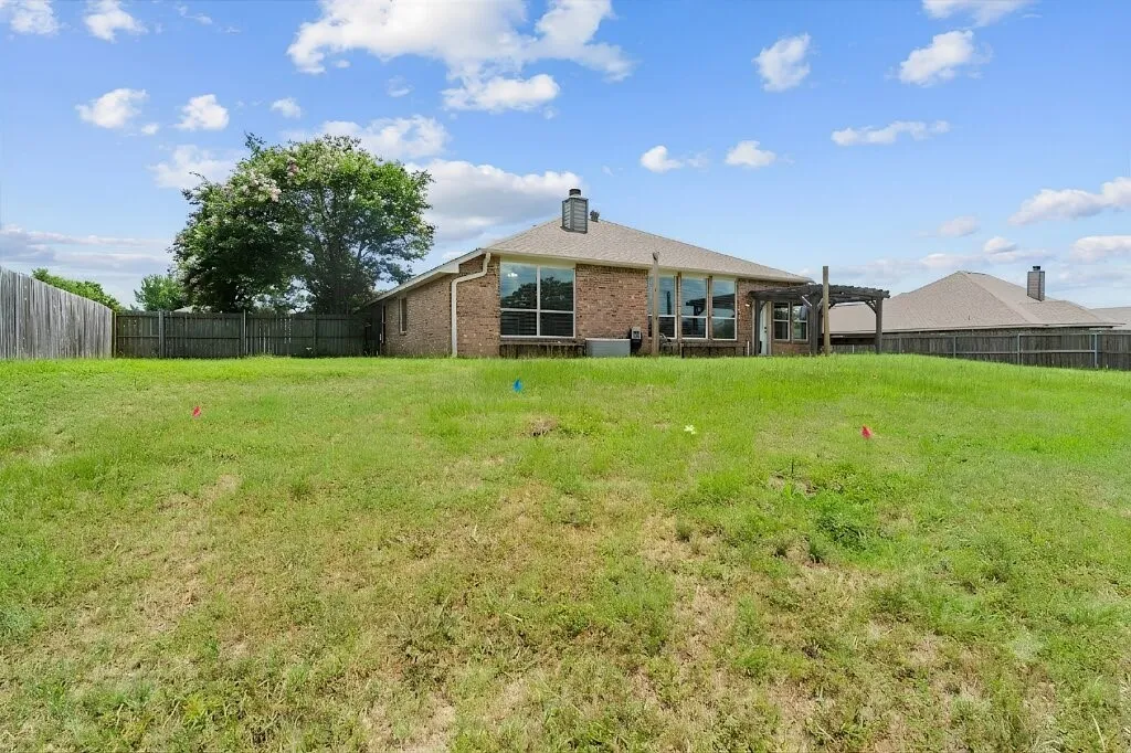 Expansive green space with a brick exterior, large windows, and a wooden pergola structure