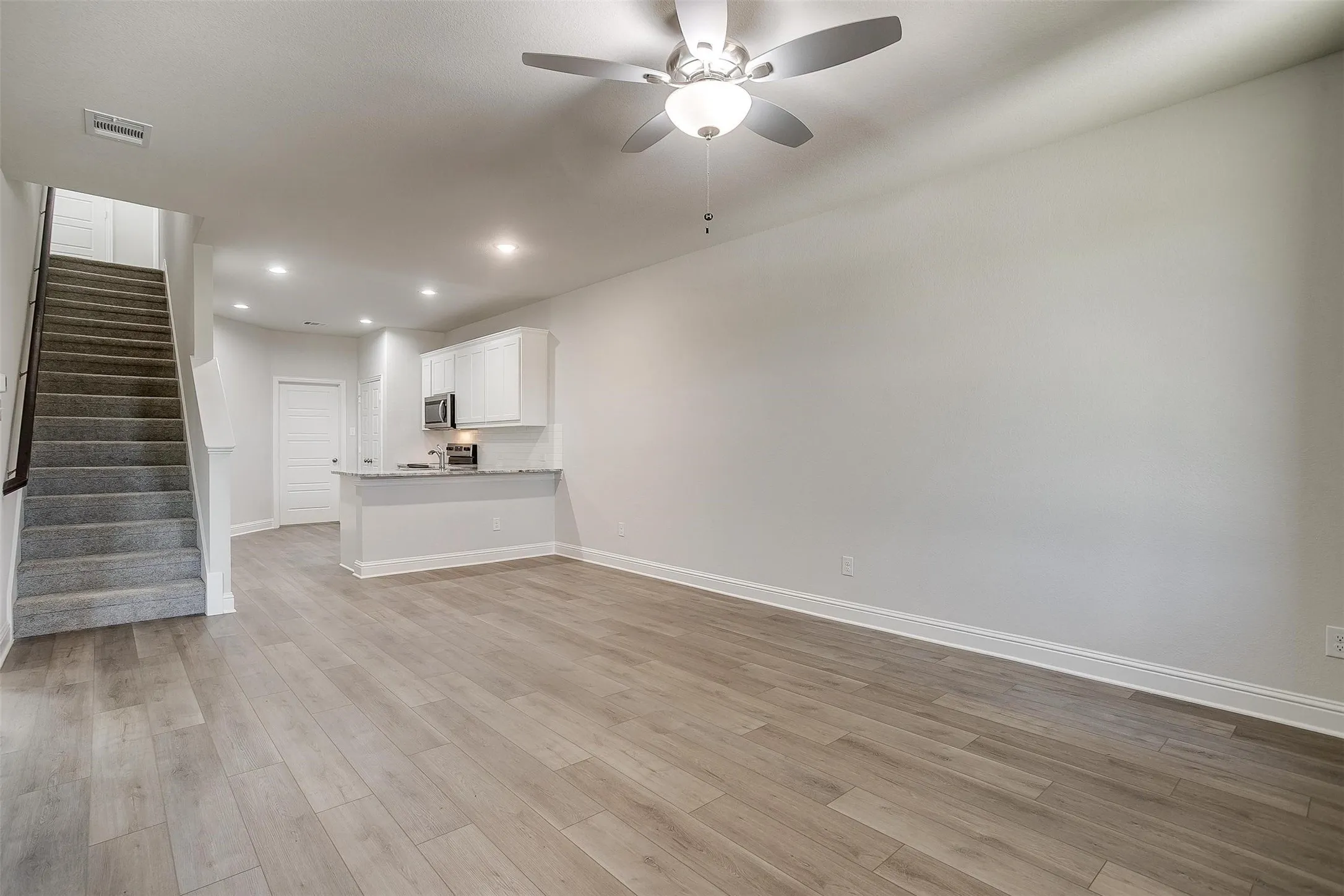 Expansive room with wood-finish flooring, recessed lighting, and a ceiling fan