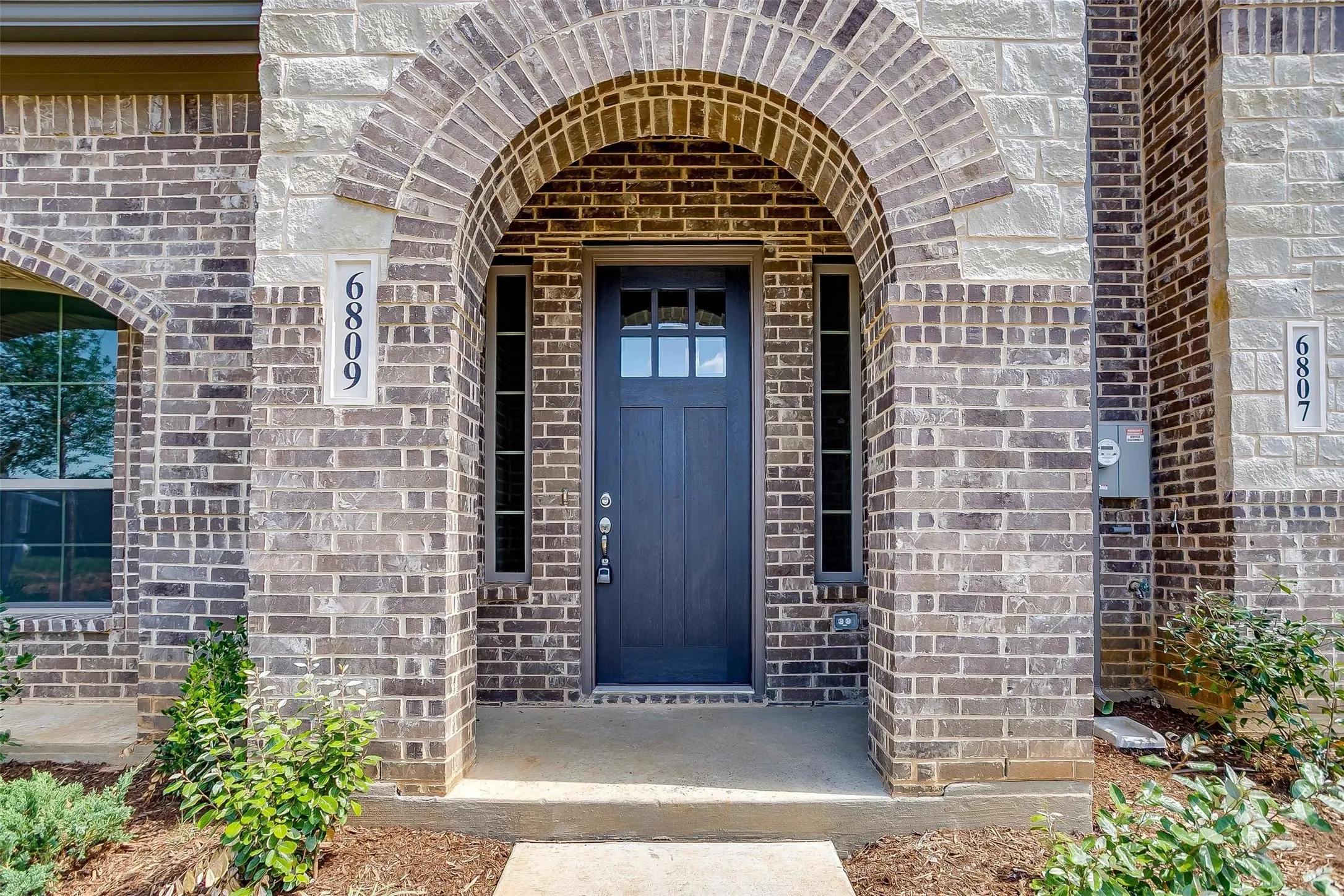 Brick and stone exterior featuring an arched entryway
