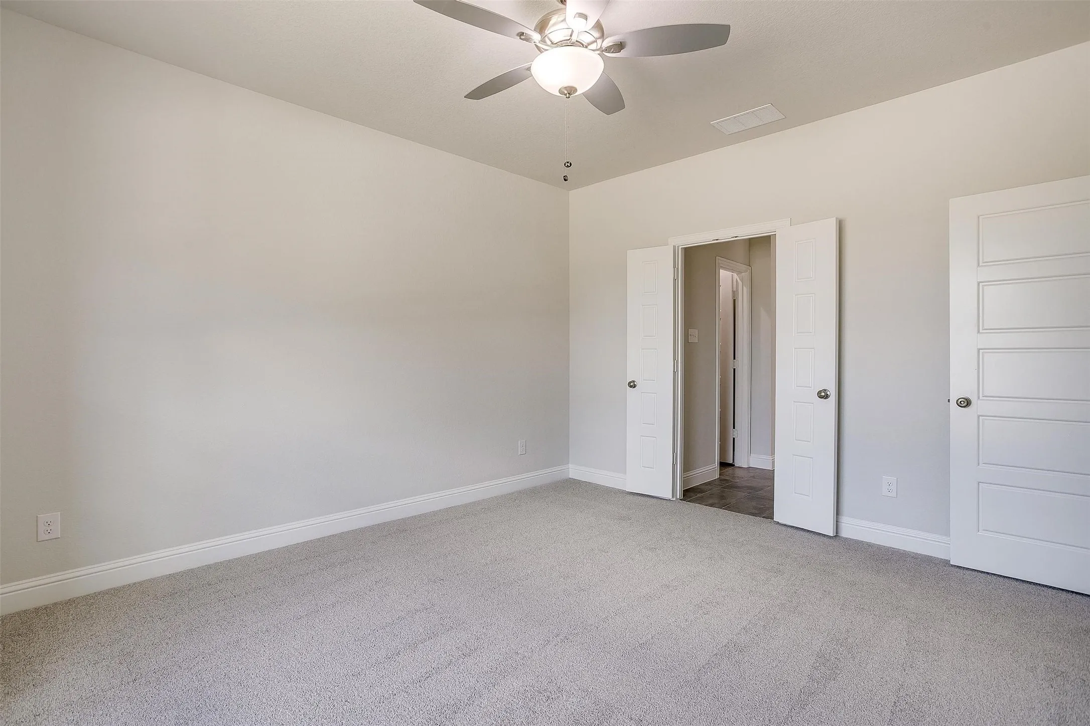 Plush carpeting, neutral wall color, and a ceiling fan with integrated lighting
