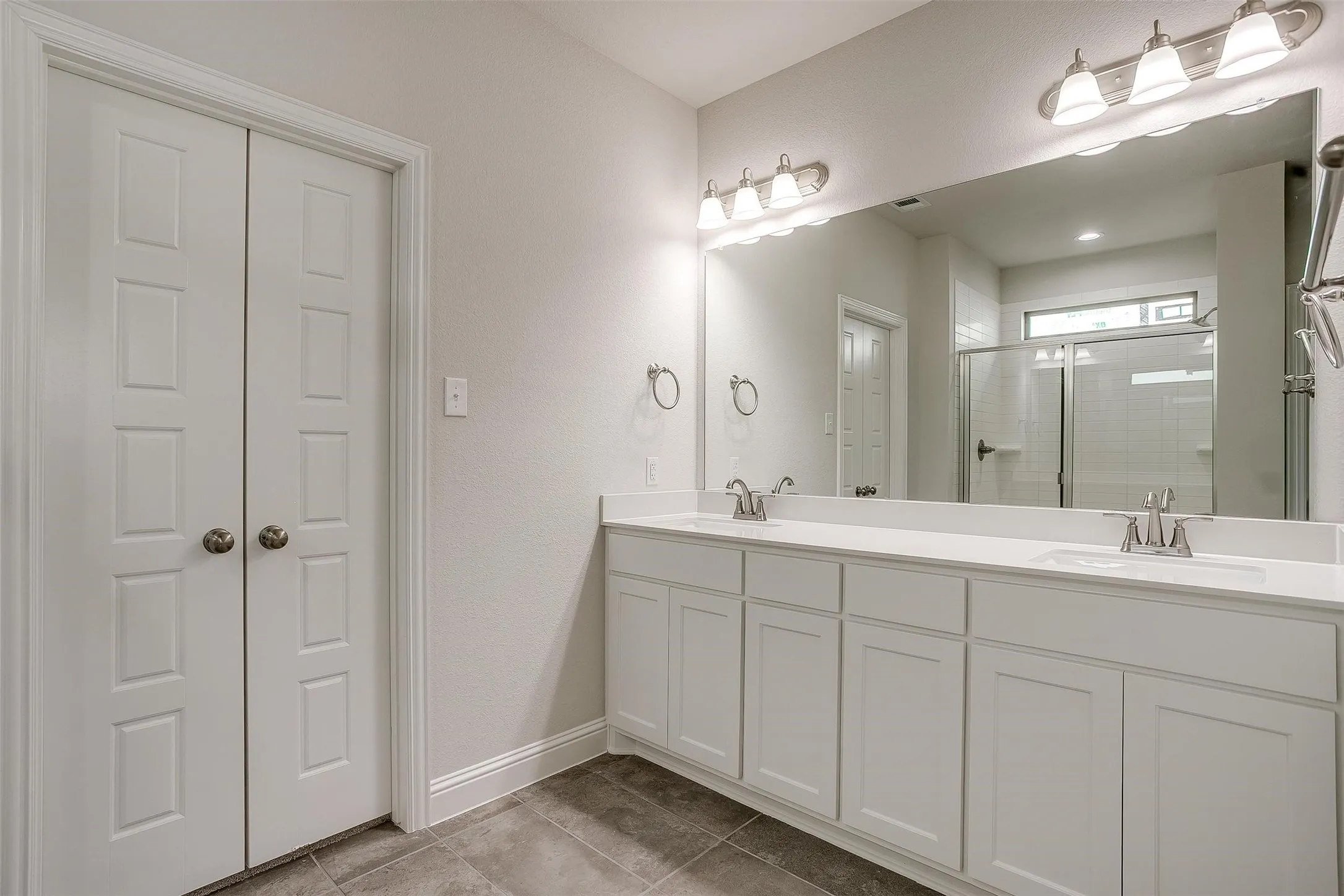Double vanity with dual sinks and chrome fixtures, framed by an expansive mirror