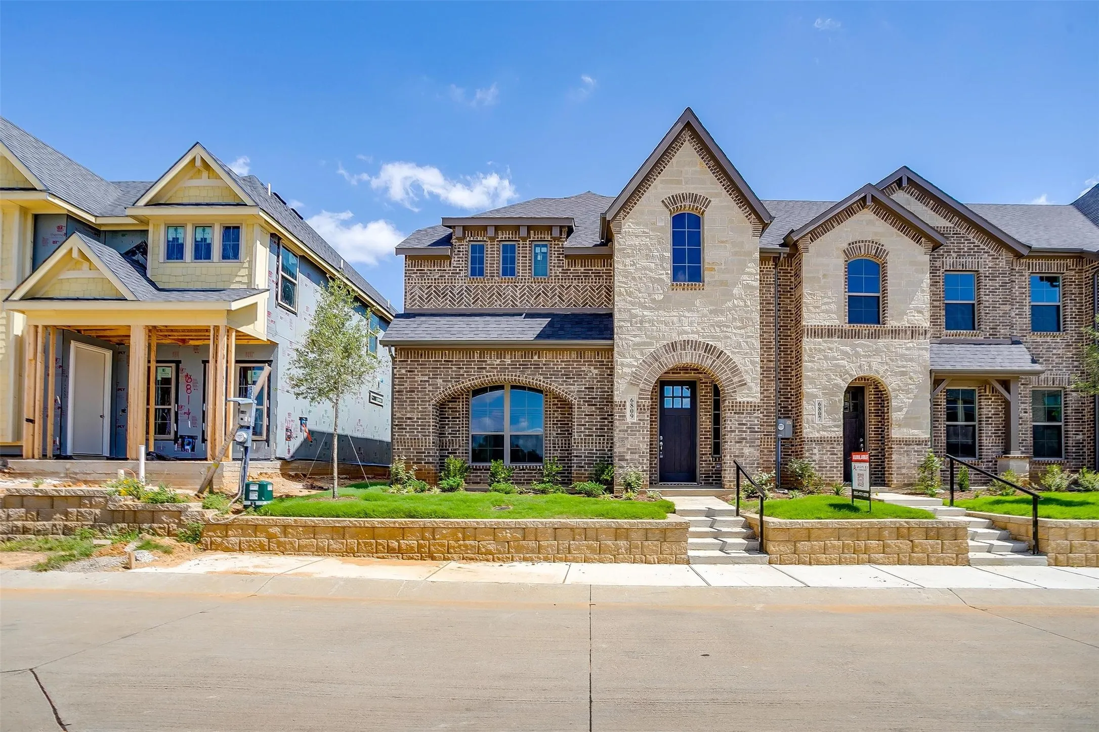 Stone and brick exterior with arched entryways, dark shingles, and multiple window styles