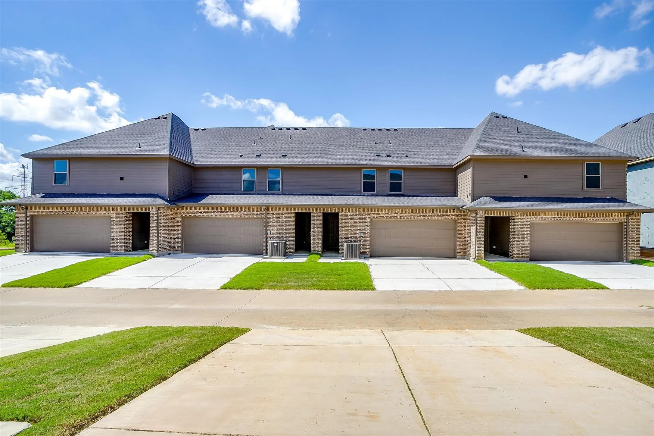 Multi-unit residence featuring a brick facade, attached garages, and a paved driveway