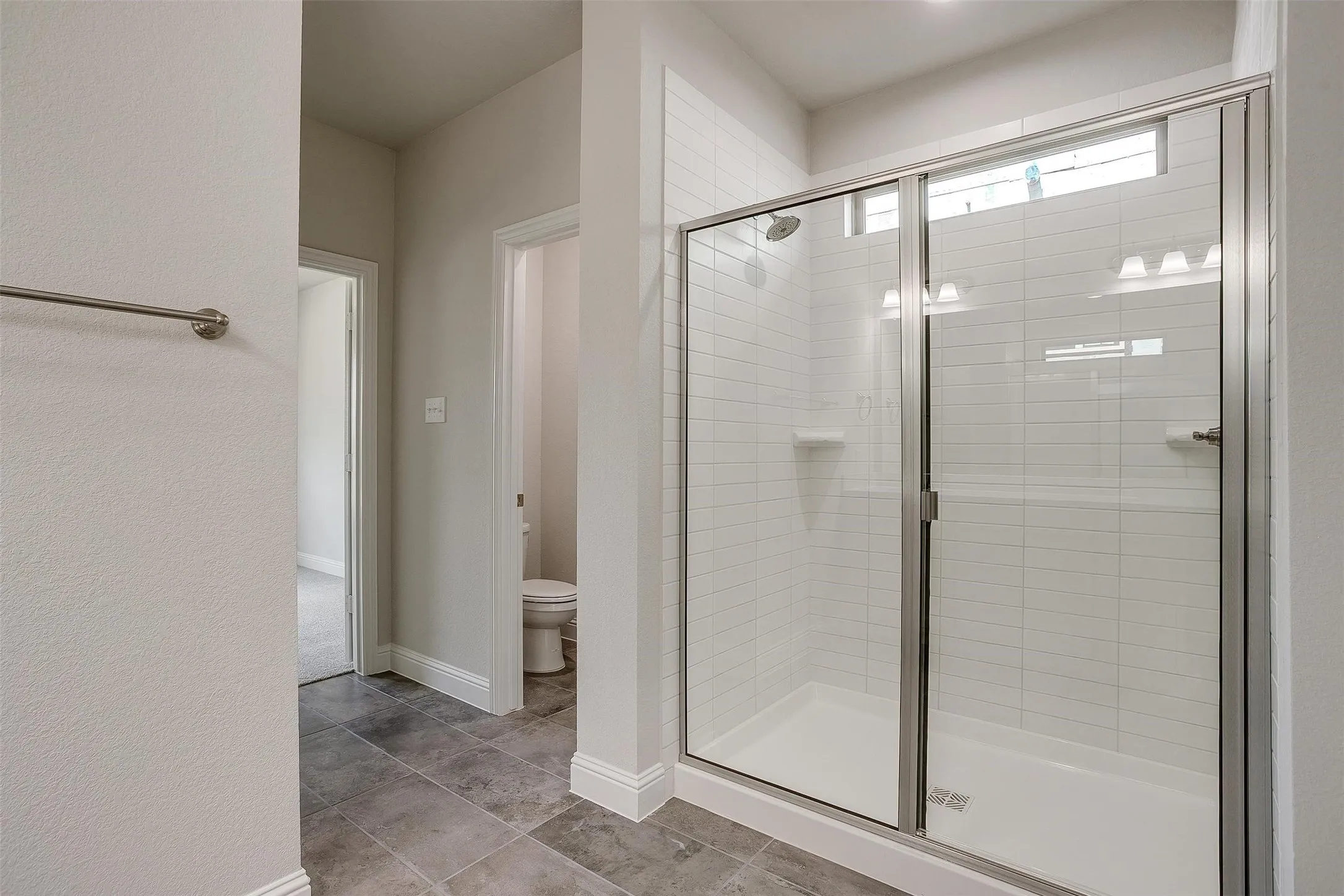 Walk-in shower with clear glass enclosure and subway tile surround